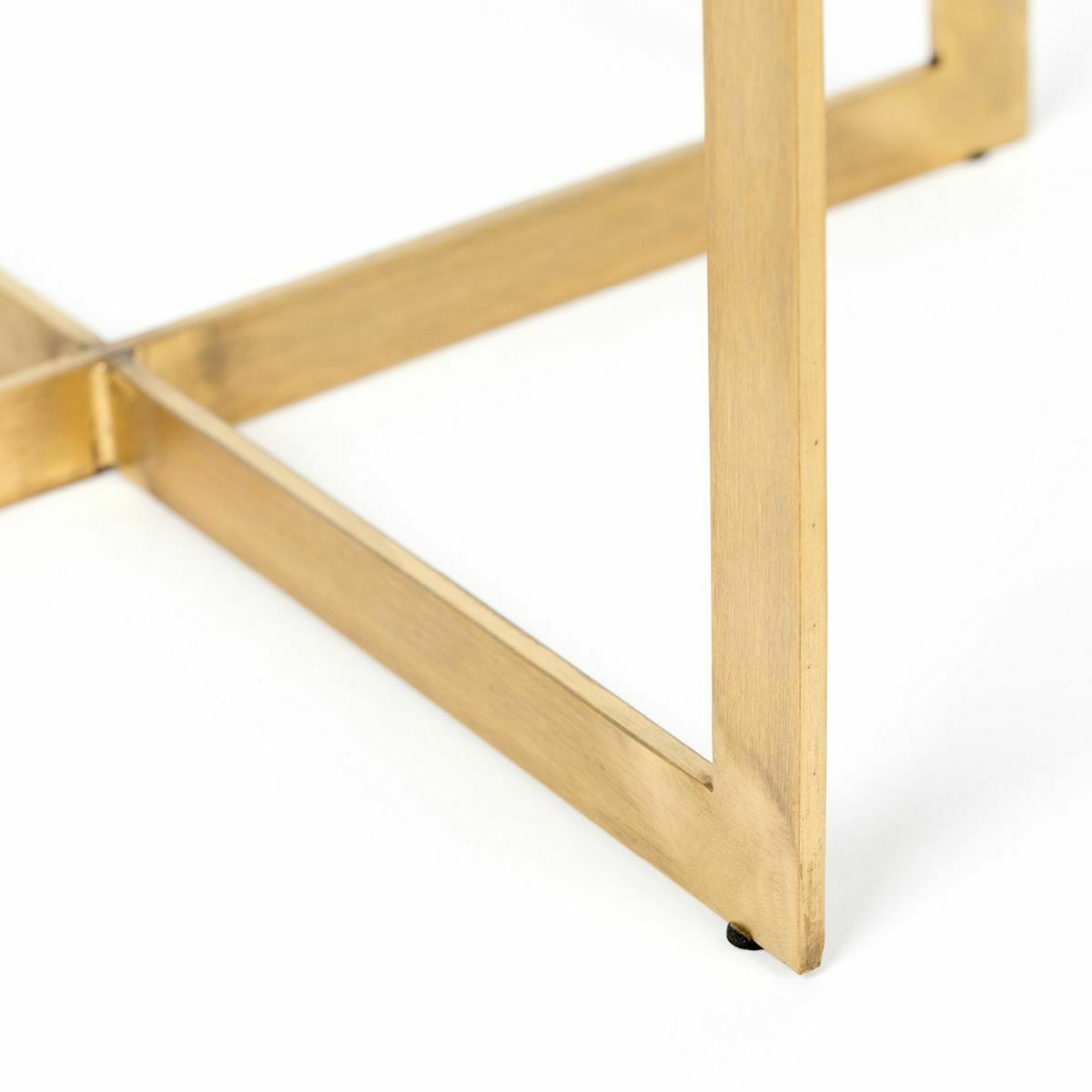 Untere Tischpartie mit goldfarbenem Gestell in dreieckiger Form  geometrisch angeordnet  auf weißem Boden stehend