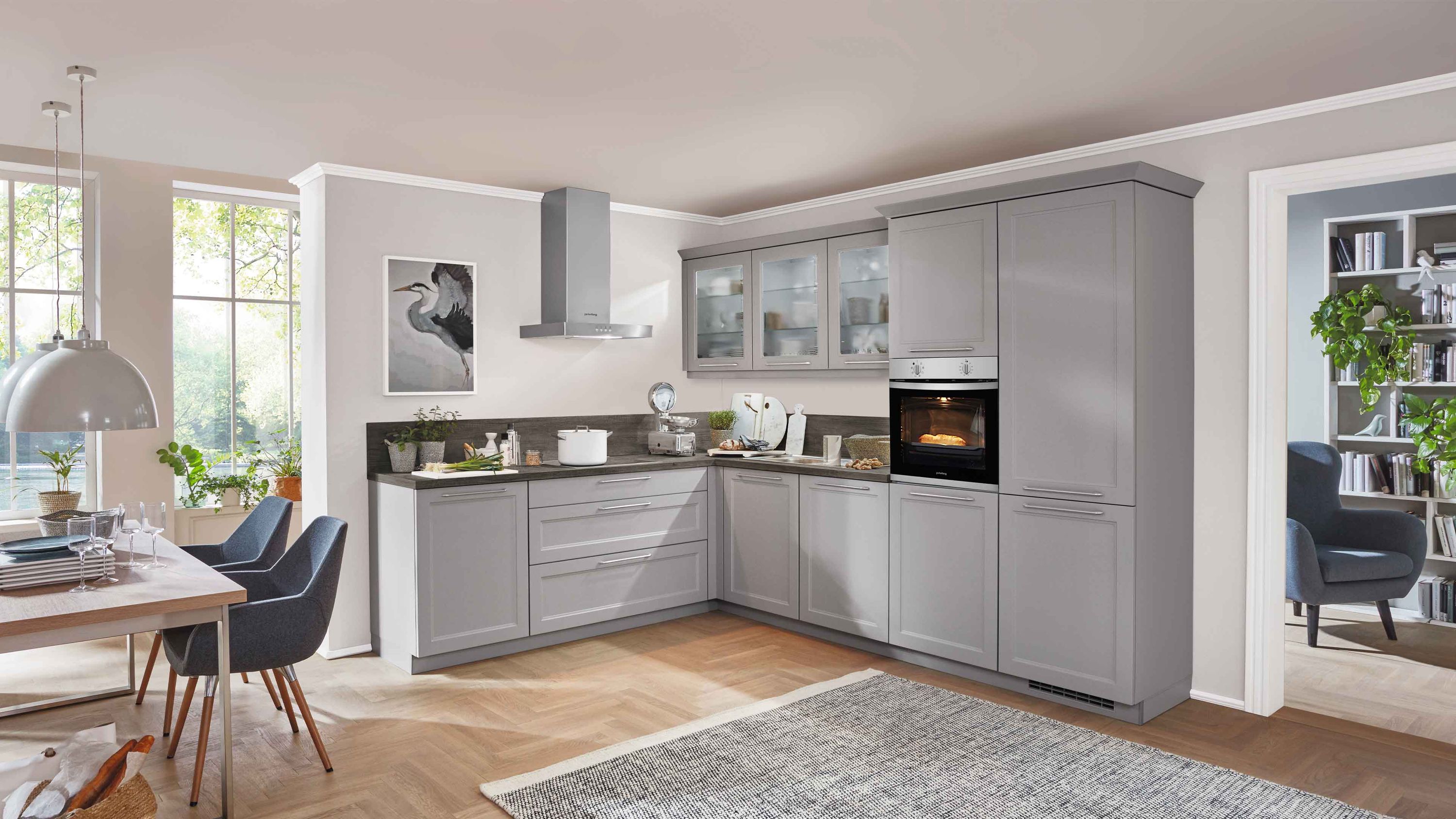 Moderne L-förmige Küche in Grau mit Glasoberschränken und integriertem Backofen.