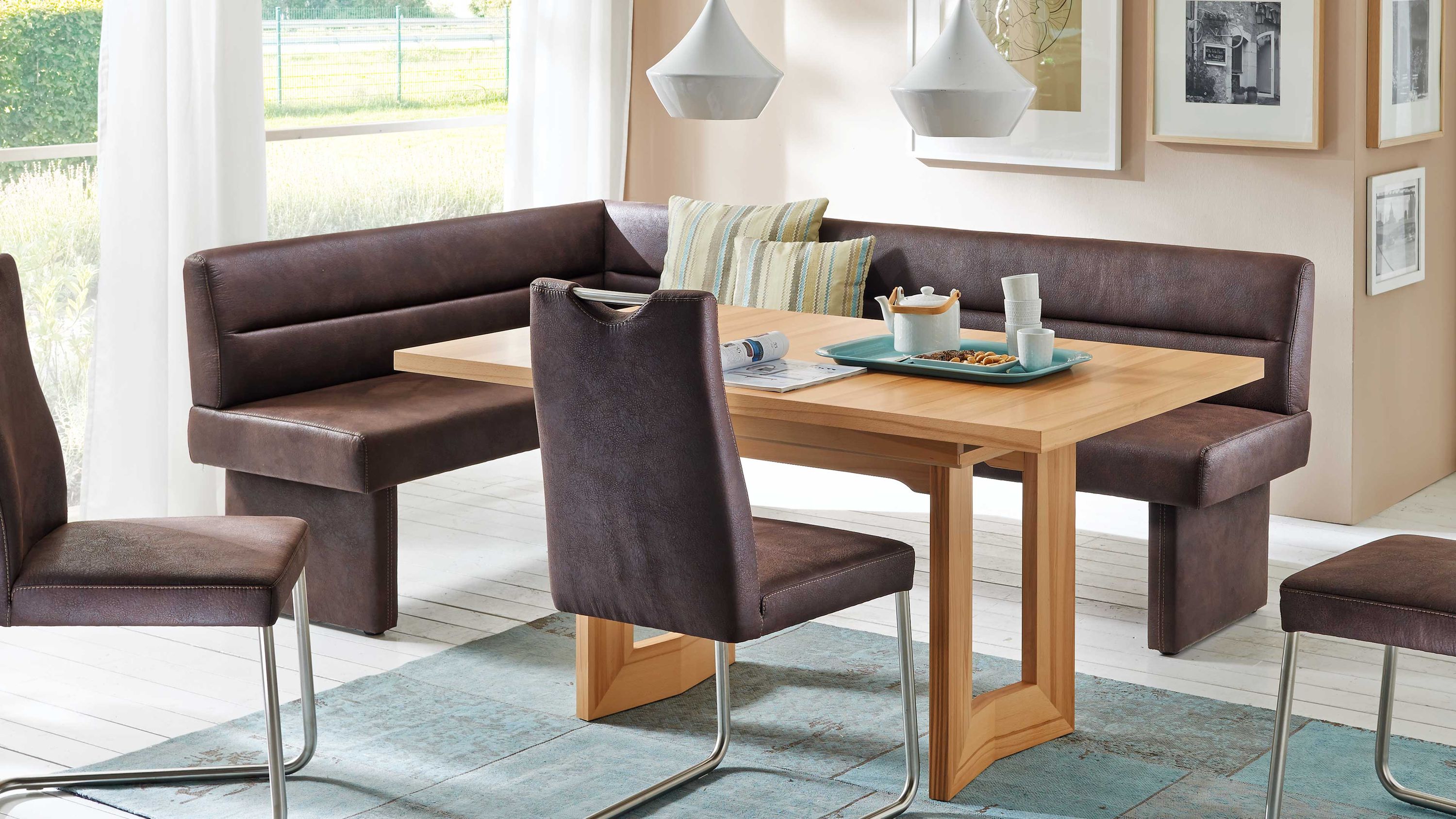 Funktionstisch aus hellem Holz mit braunen Polsterbänken und Stühlen in einem Esszimmer