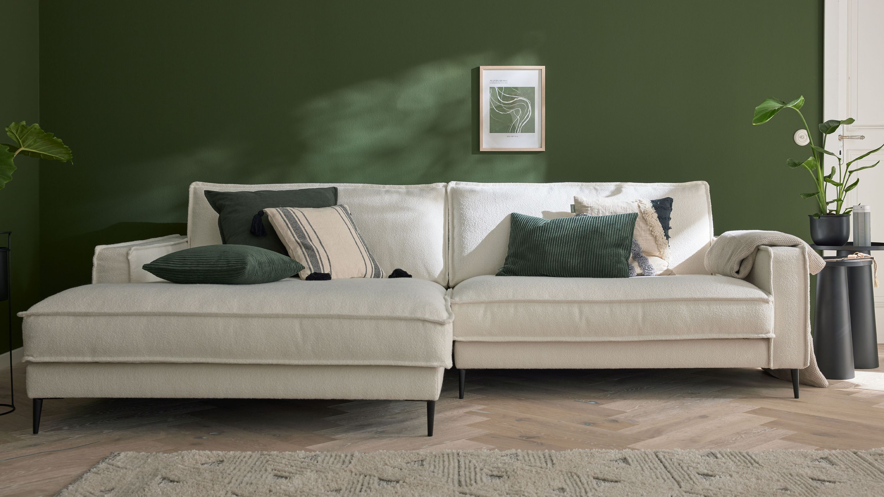 Ecksofa mit weißem Stoffbezug und schwarzen Metallfüßen dekoriert mit Kissen in verschiedenen Farben