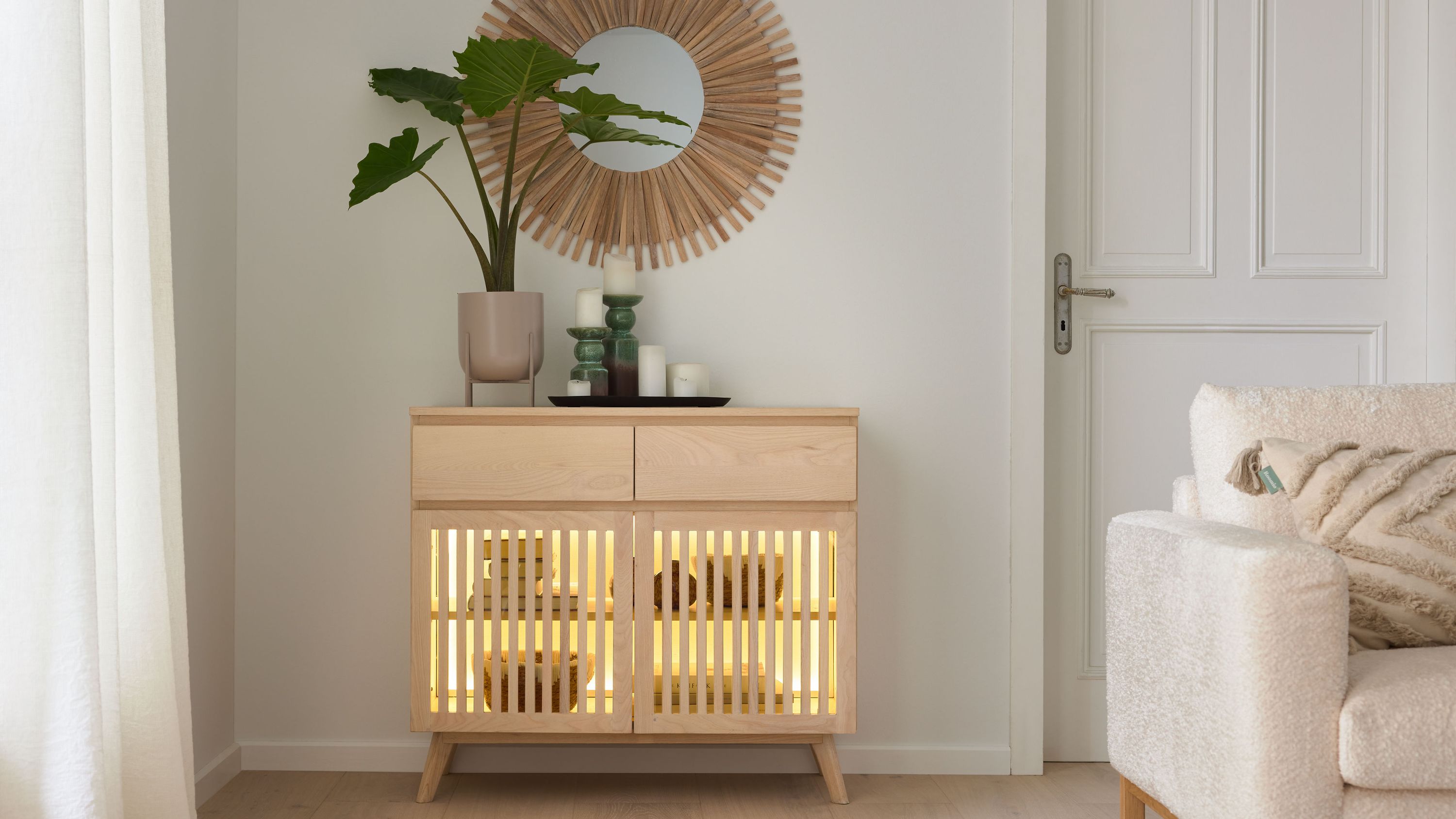Sideboard mit Lamellentüren in hellholzfarben Sideboard mit zwei Schubladen und zwei Türen mit Lamellen in hellholzfarben mit Dekoration und Spiegel an weißer Wand