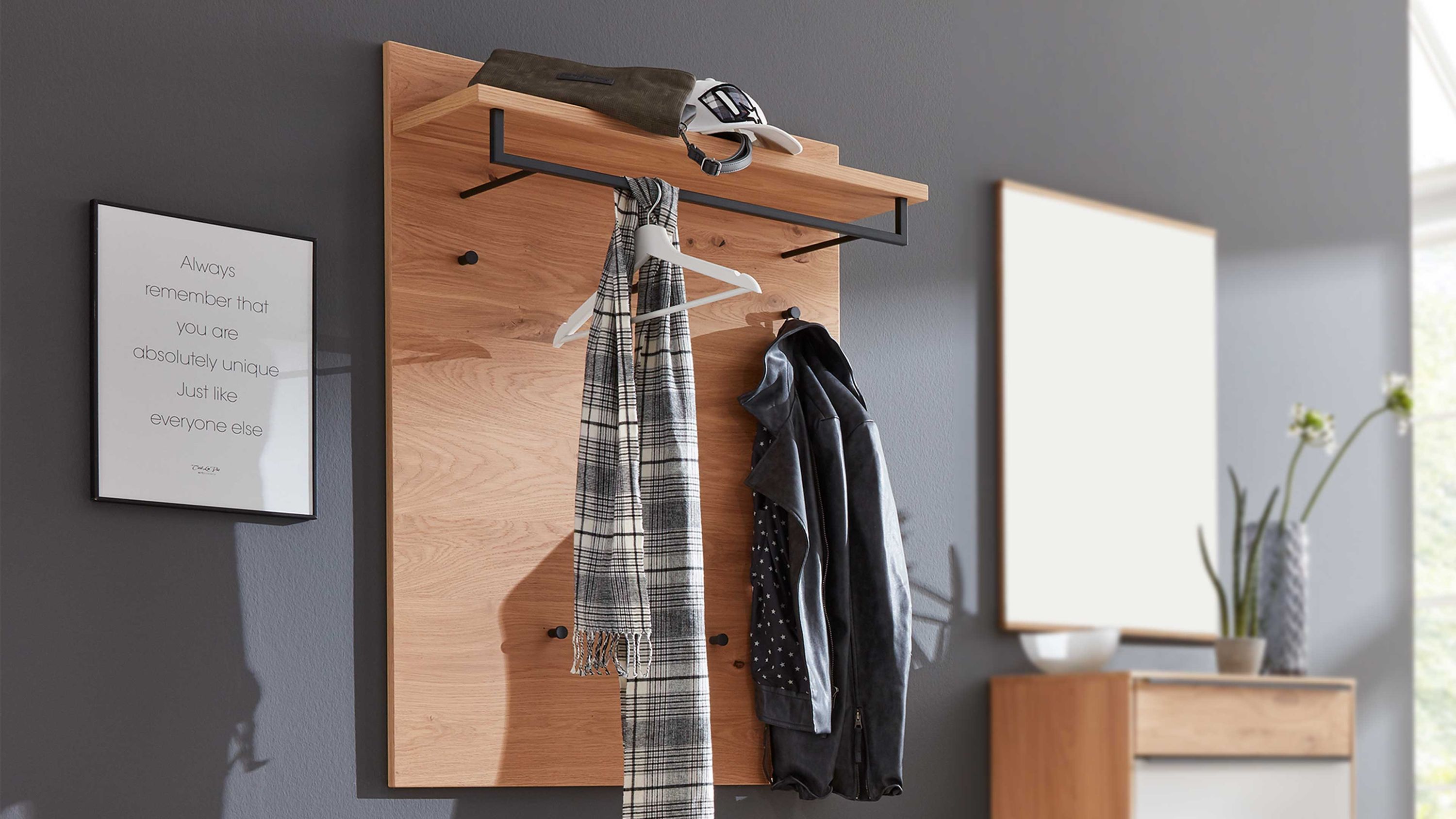 Wandgarderobe aus hellem Holz mit schwarzem Metallgestell Haken und Ablagefläche an der Kleidung und Accessoires hängen