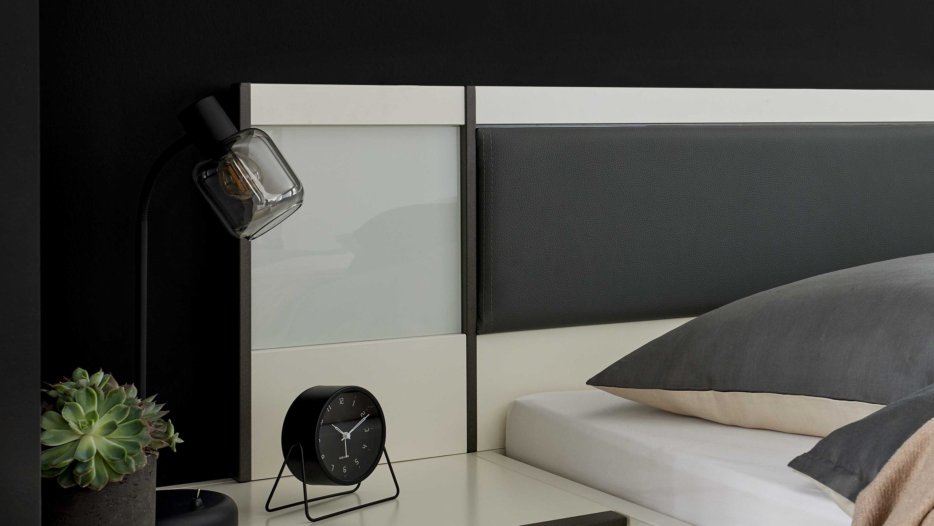 Zweiteiliges Paneel-Set aus weißem Glas und Holz am Bett Zweiteiliges Paneel-Set mit weißem Glas und Holz neben Bett mit grauem Kissen und schwarzer Wandlampe