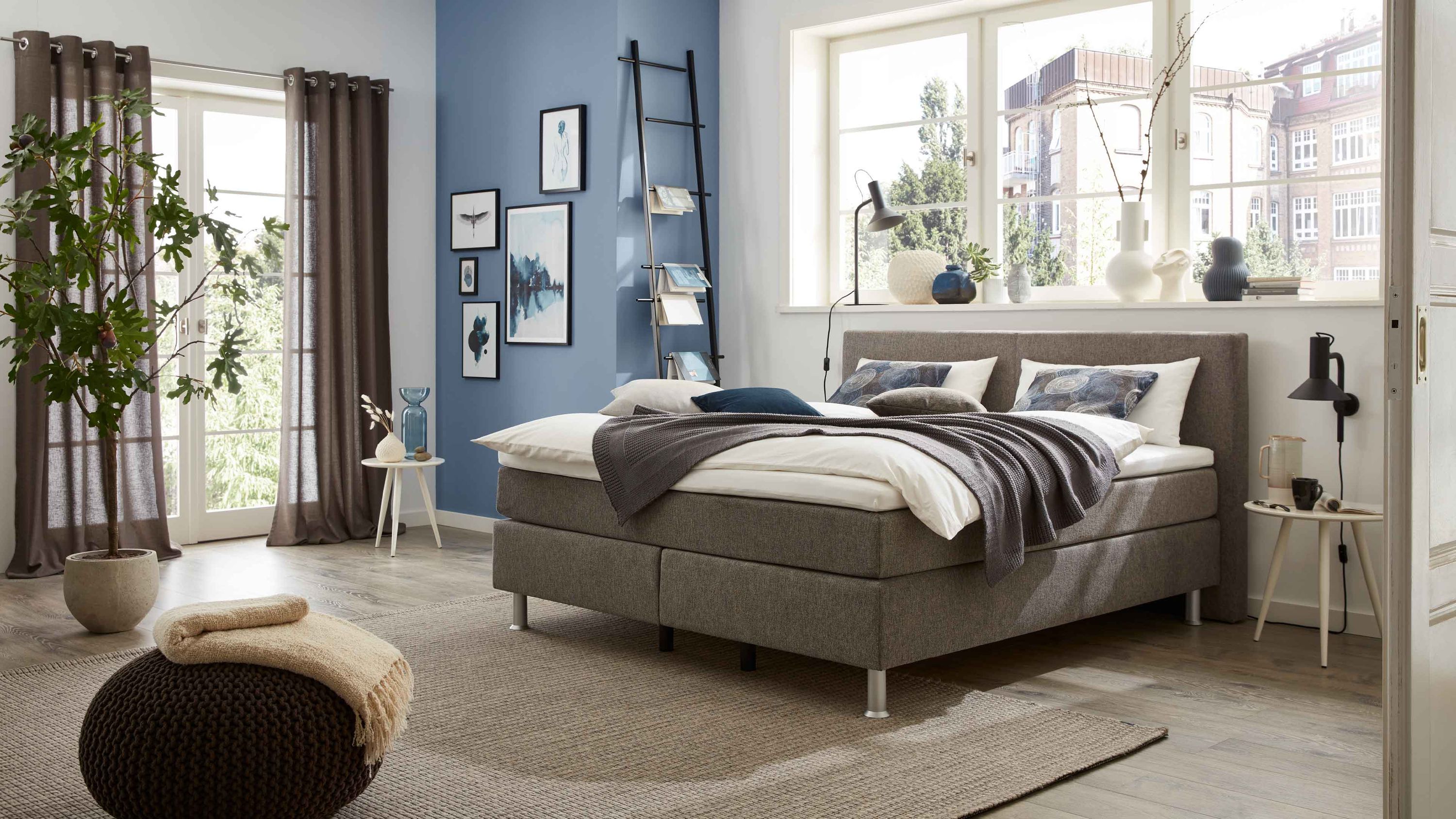 Boxspringbett mit grauem Stoffbezug Kopfteil und Metallfüßen in modernem Schlafzimmer