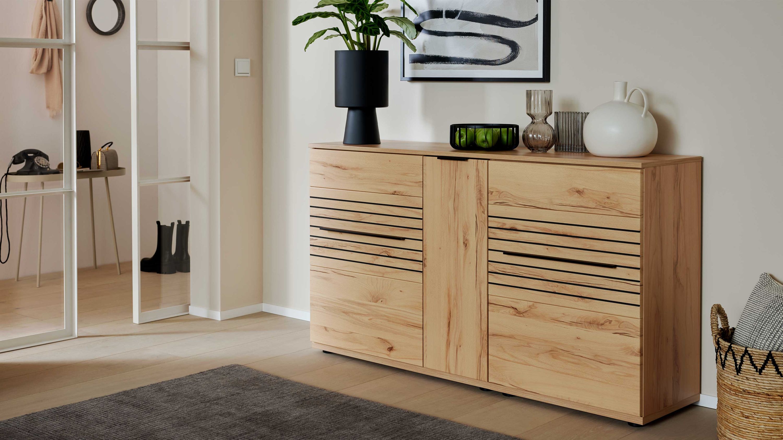 Sideboard mit drei Türen in hellbrauner Holzoptik mit schwarzen Griffleisten in modernem Wohnzimmer