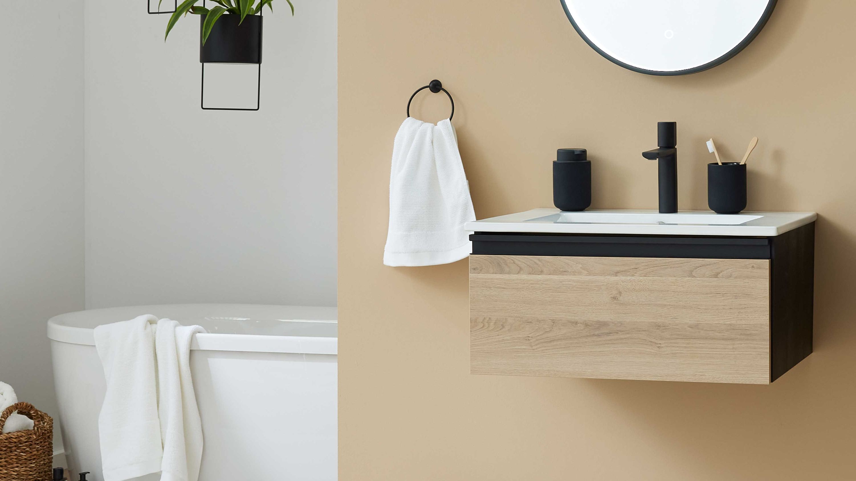 Hängender Waschtisch mit naturfarbener Holzfront und weißem Becken an beige Wand mit rundem Spiegel