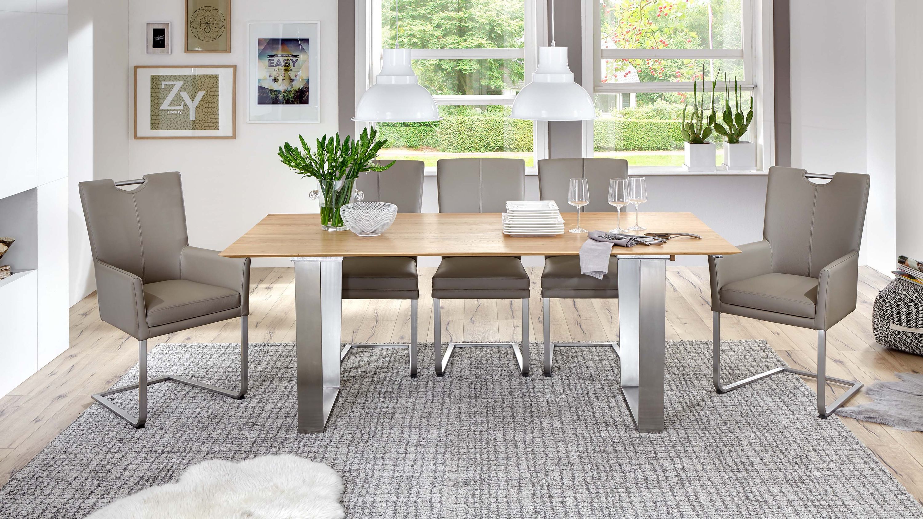 Sechs steinfarbene Stühle mit Armlehnen und Edelstahlgestell um einen rechteckigen Holztisch in hellem Esszimmer