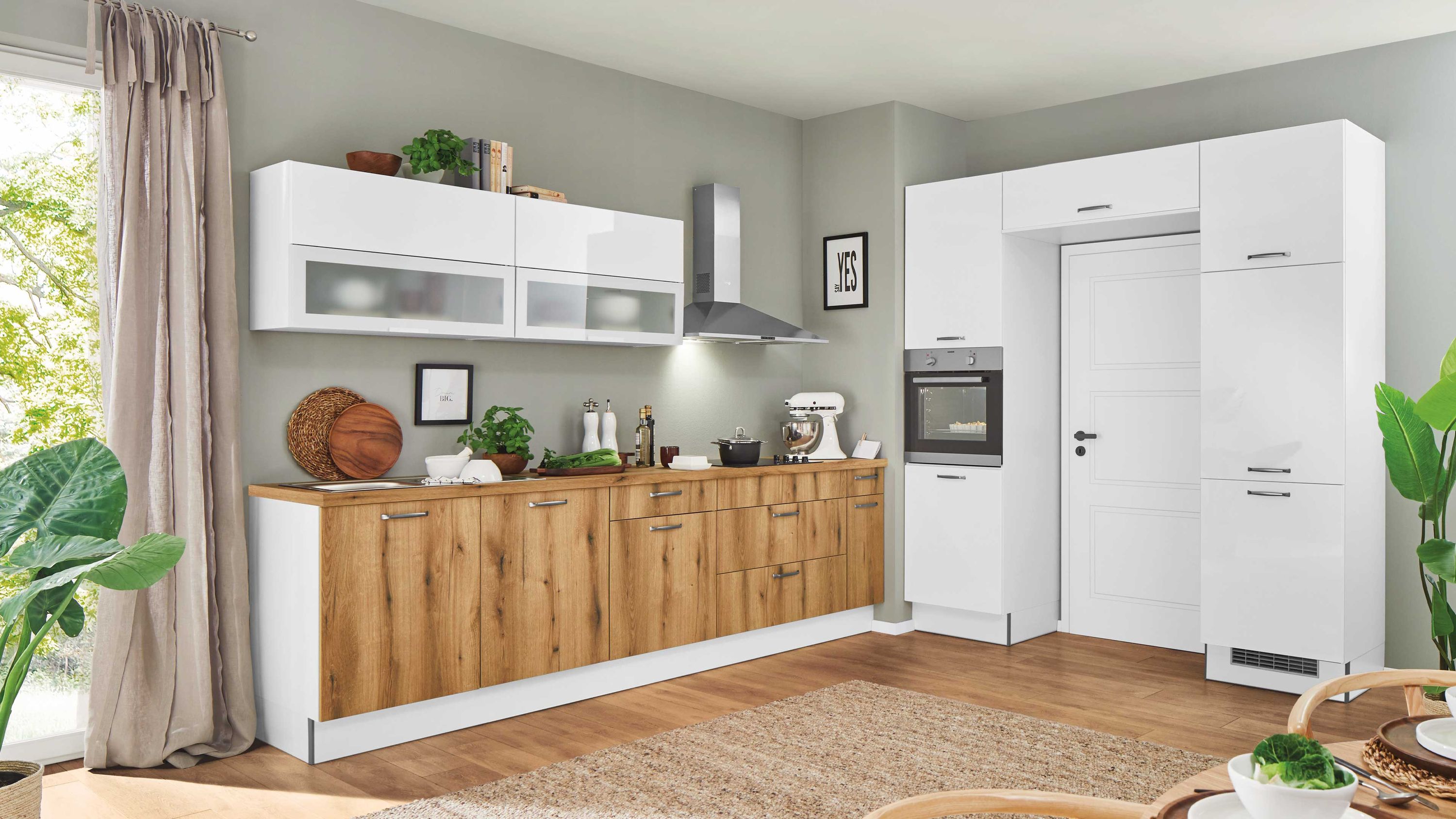 Moderne Küche mit weißen Hochglanzschränken und Holzfronten daneben hochgebauter Backofen.
