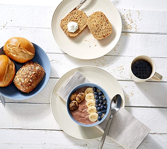 Frühstück mit Brötchen, Bowl und Kaffee auf weißem Tisch Frühstück auf weißem Holztisch mit Brötchen, Brot mit Aufstrich, Bowl mit Banane, Blaubeeren und Tasse Kaffee