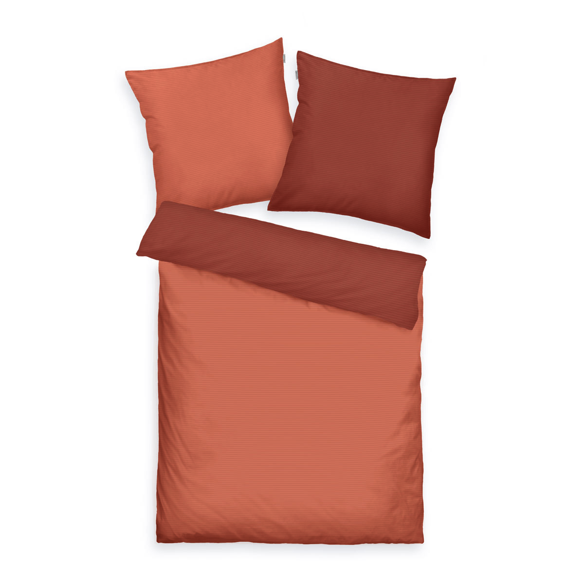 Draufsicht auf Bett mit zwei Kissen und Decke jeweils orange auf einer Seite dunkelorange auf der anderen