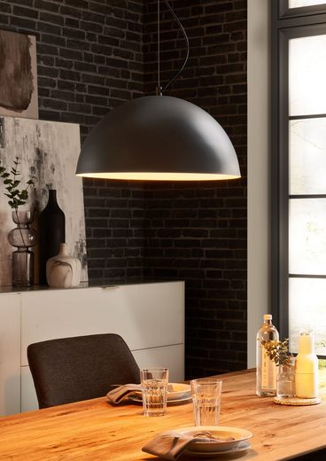 Zeitgemäßer Essbereich mit Pendelleuchte Große schwarze Pendelleuchte über gedecktem Holztisch im modernen Essbereich, aus frontaler Perspektive fotografiert