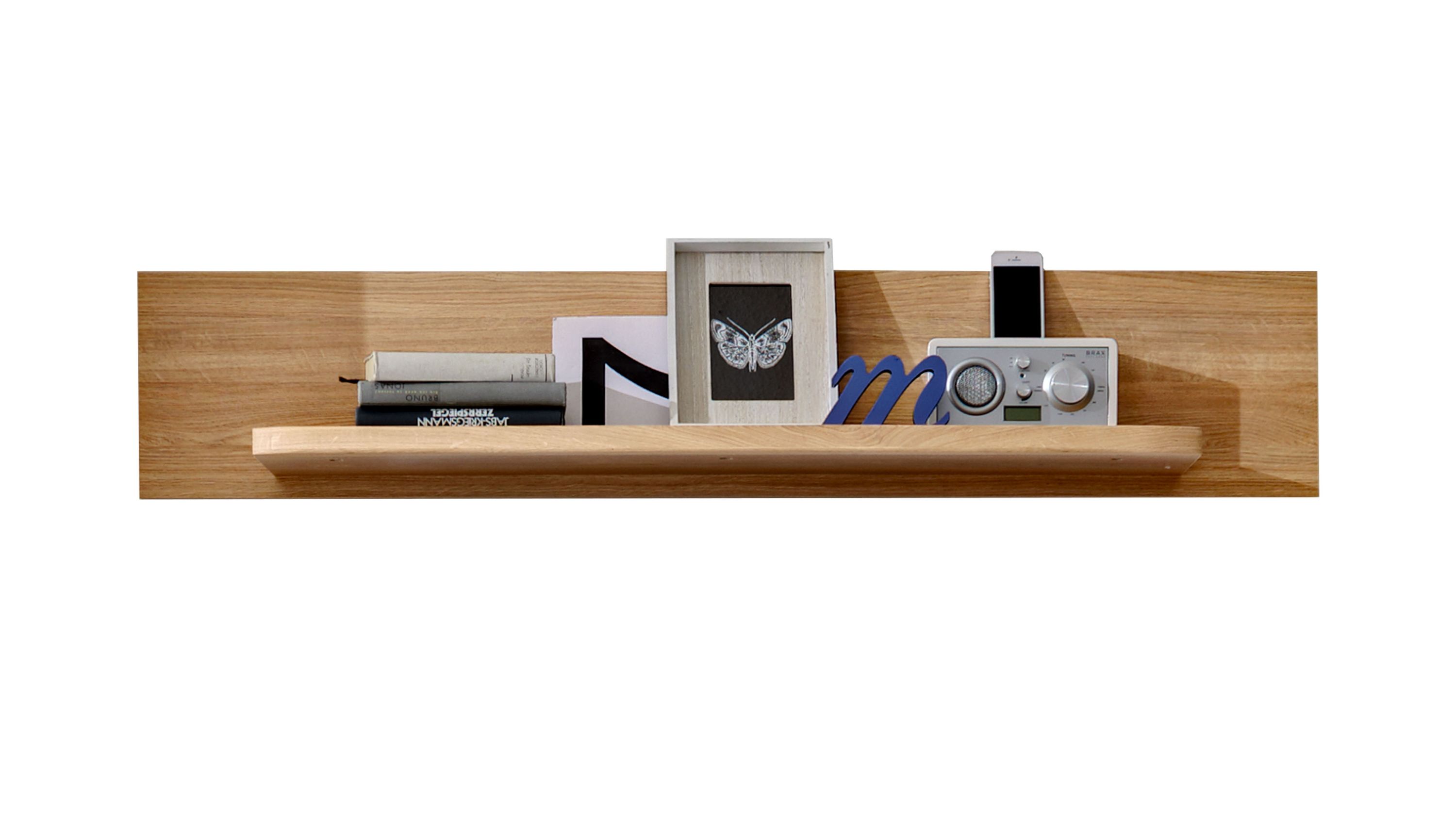 Wandboard mit Regal in Holzoptik Rechteckiges Wandboard mit breitem Regal in hellbrauner Holzoptik darauf Bücher Bilderrahmen und Radio