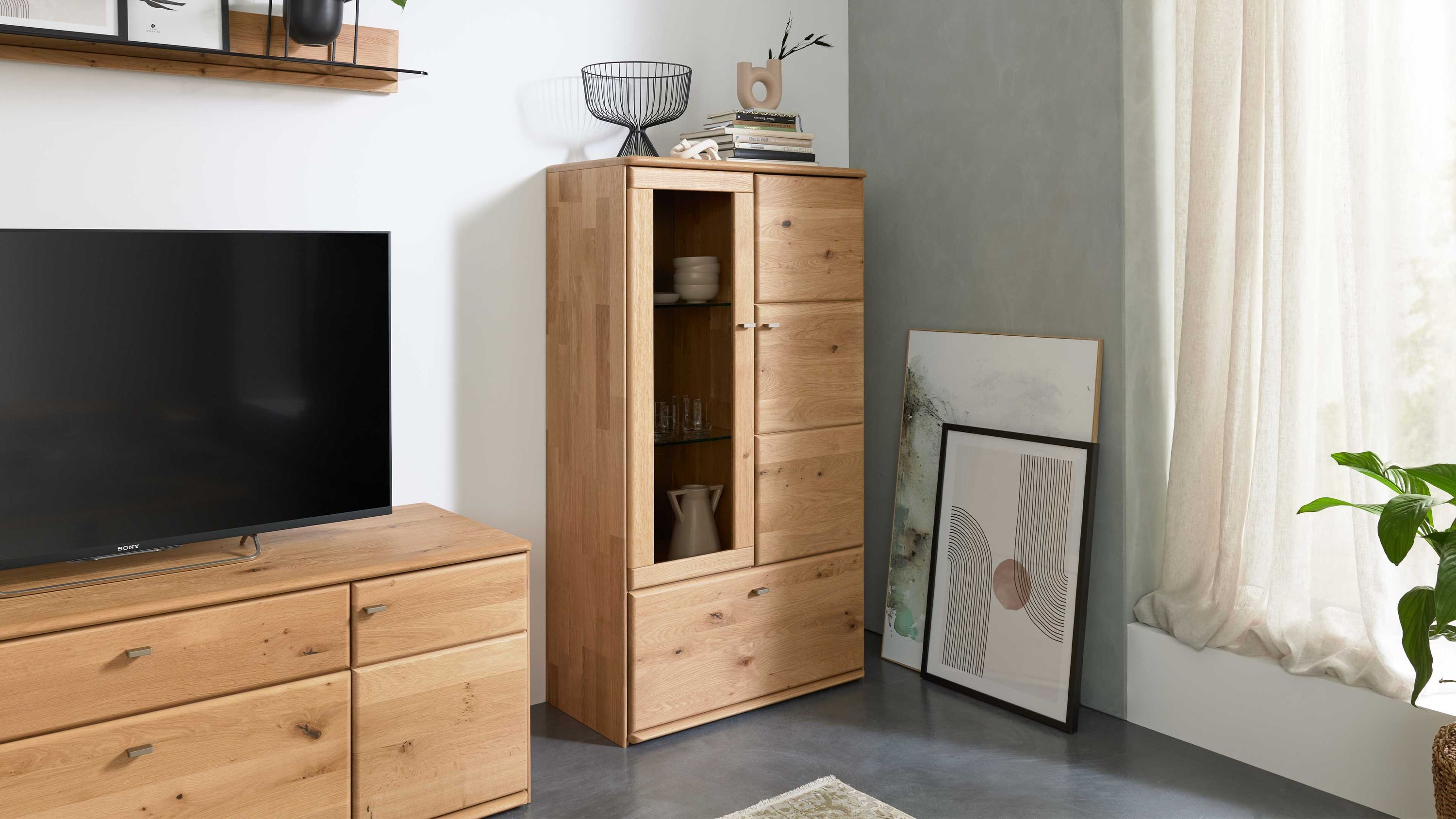 Highboard mit Türen und Schubladen in Holzoptik Helles Highboard mit zwei Türen zwei Schubladen und Glaseinsatz Holzoptik stehend im Wohnzimmer