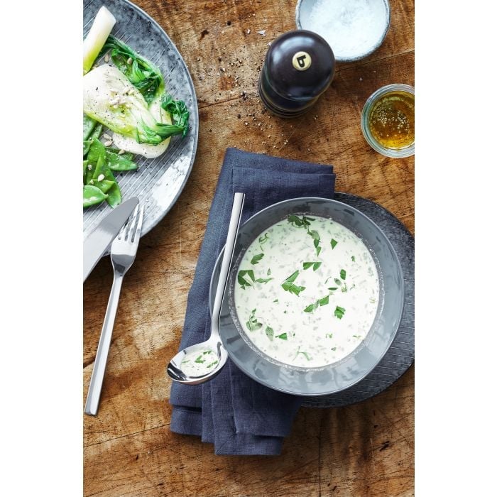 Gedeckter Tisch mit Suppe, Saucenlöffel und Beilagen aus der Vogelperspektive Draufsicht auf gedeckten Tisch mit Suppe auf Serviette Saucenlöffel Salatteller Besteck Flasche & Gefäß im Hintergrund