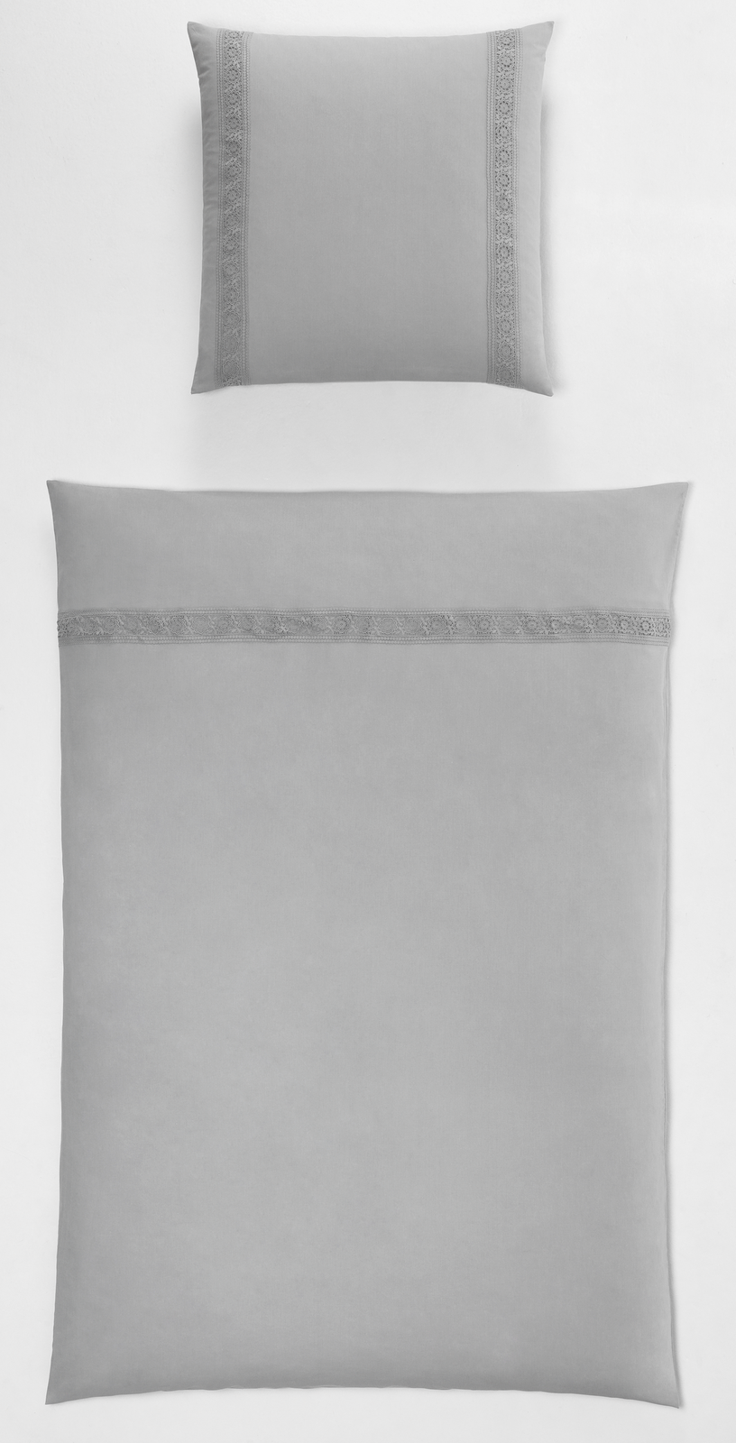 Graues Bettwäsche-Set mit Spitzenborte, bestehend aus Kissen- und Deckenbezug, auf heller Fläche von oben fotografiert