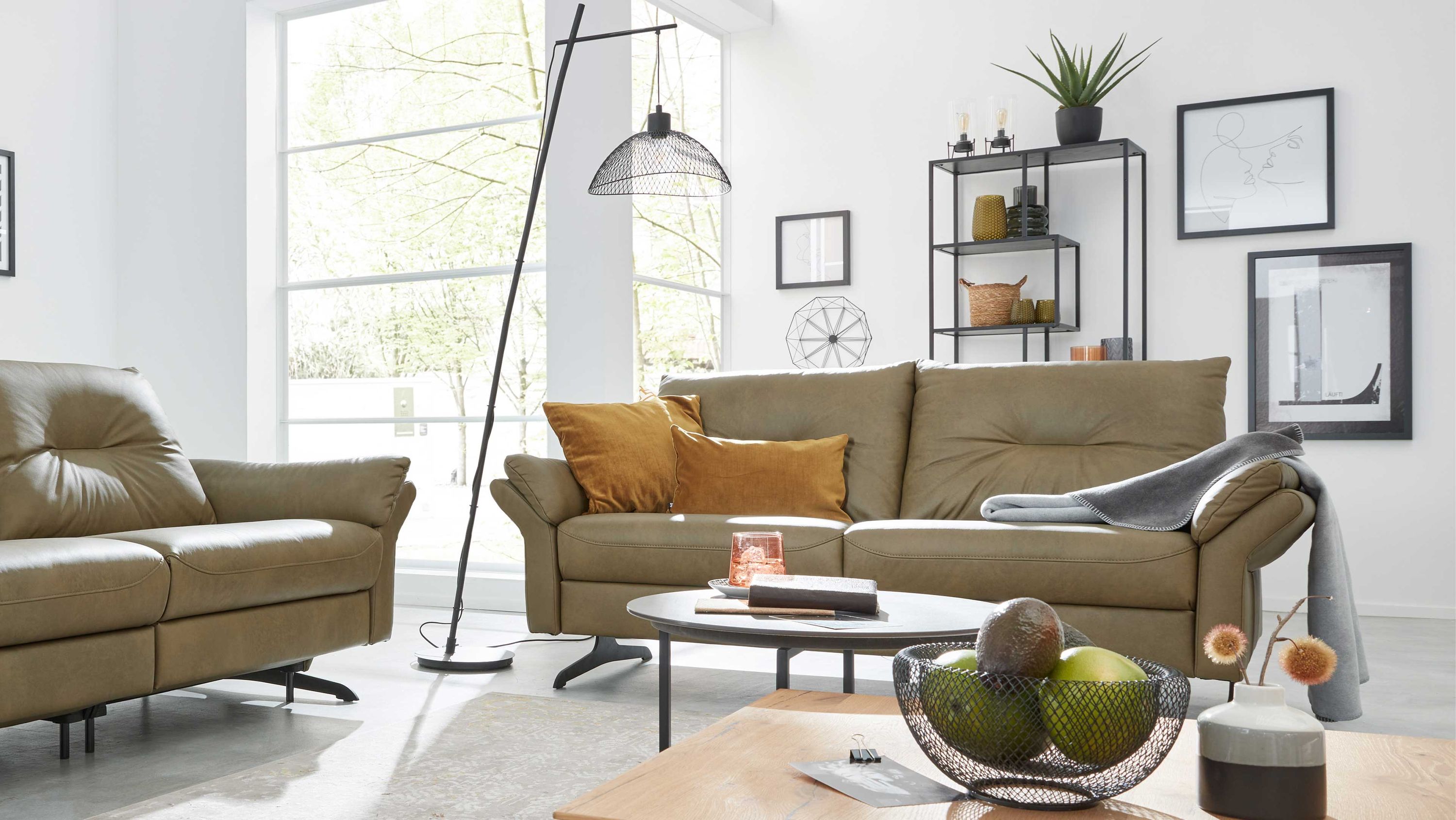 Zweisitziges Sofa aus olivgrünem Leder mit Kissen und Decke in modernem Wohnzimmer