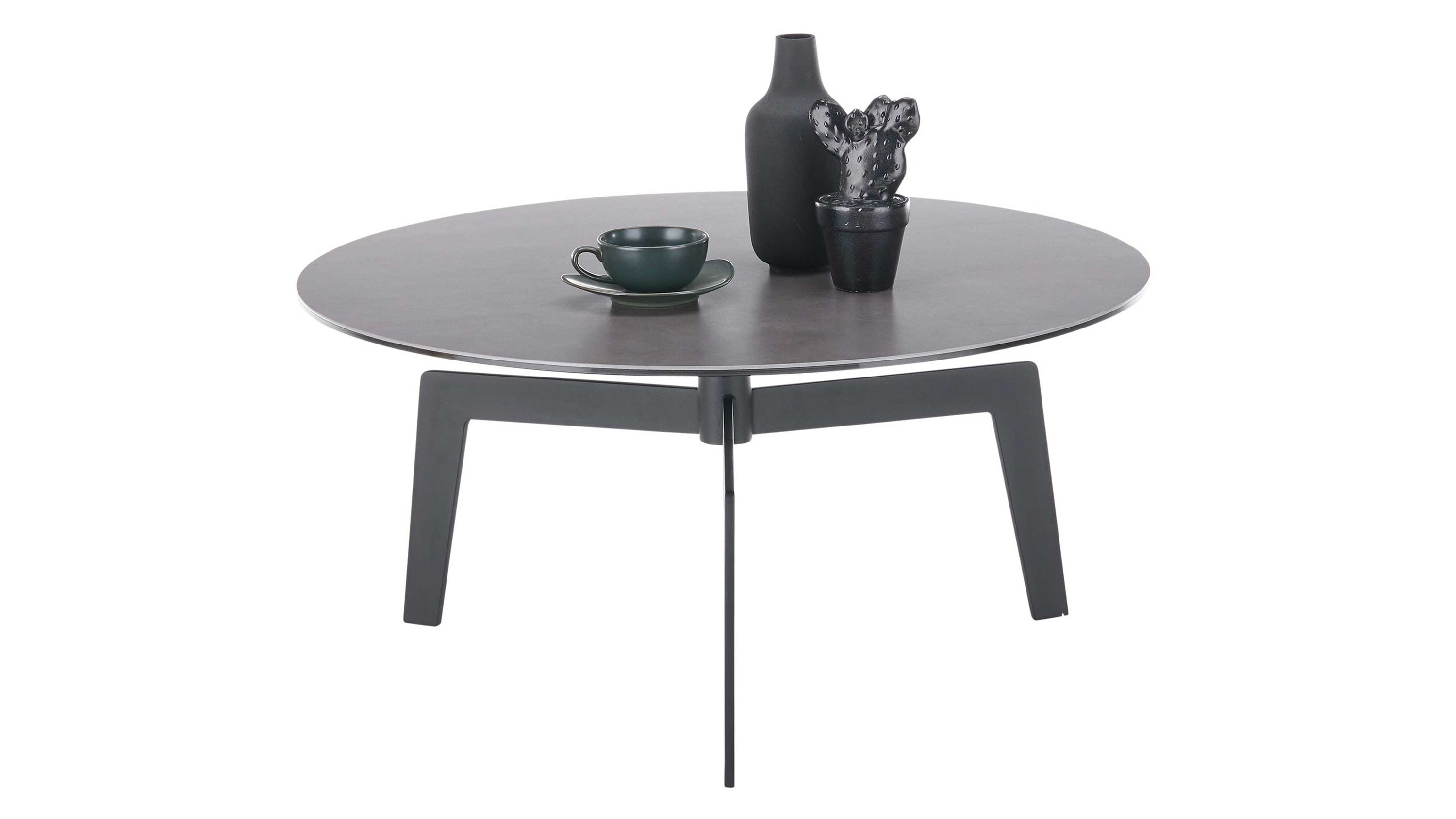Runder Couchtisch mit anthrazitfarbener Platte drei schwarzen Beinen Vase Kaktus und Tasse mit Untertasse