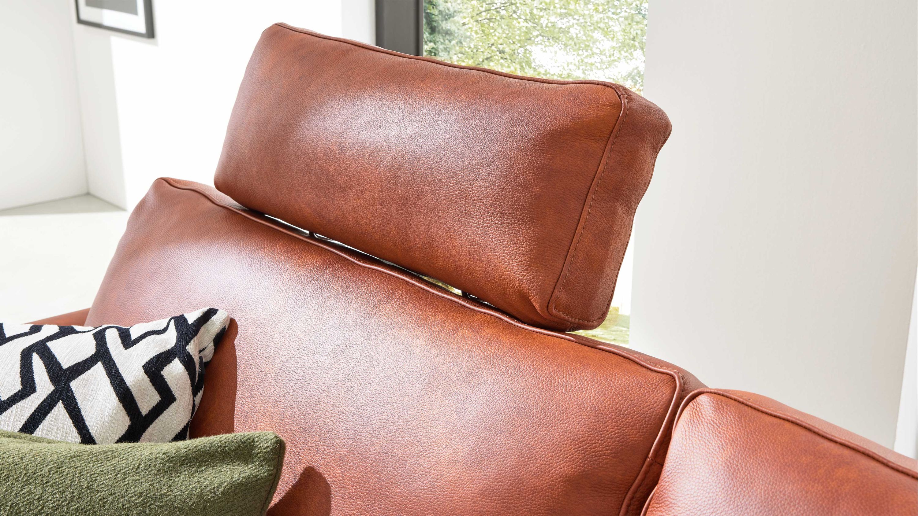Kopfstütze in rechteckiger Form aus cognacfarbenem Leder auf einem Sofa mit zwei Kissen