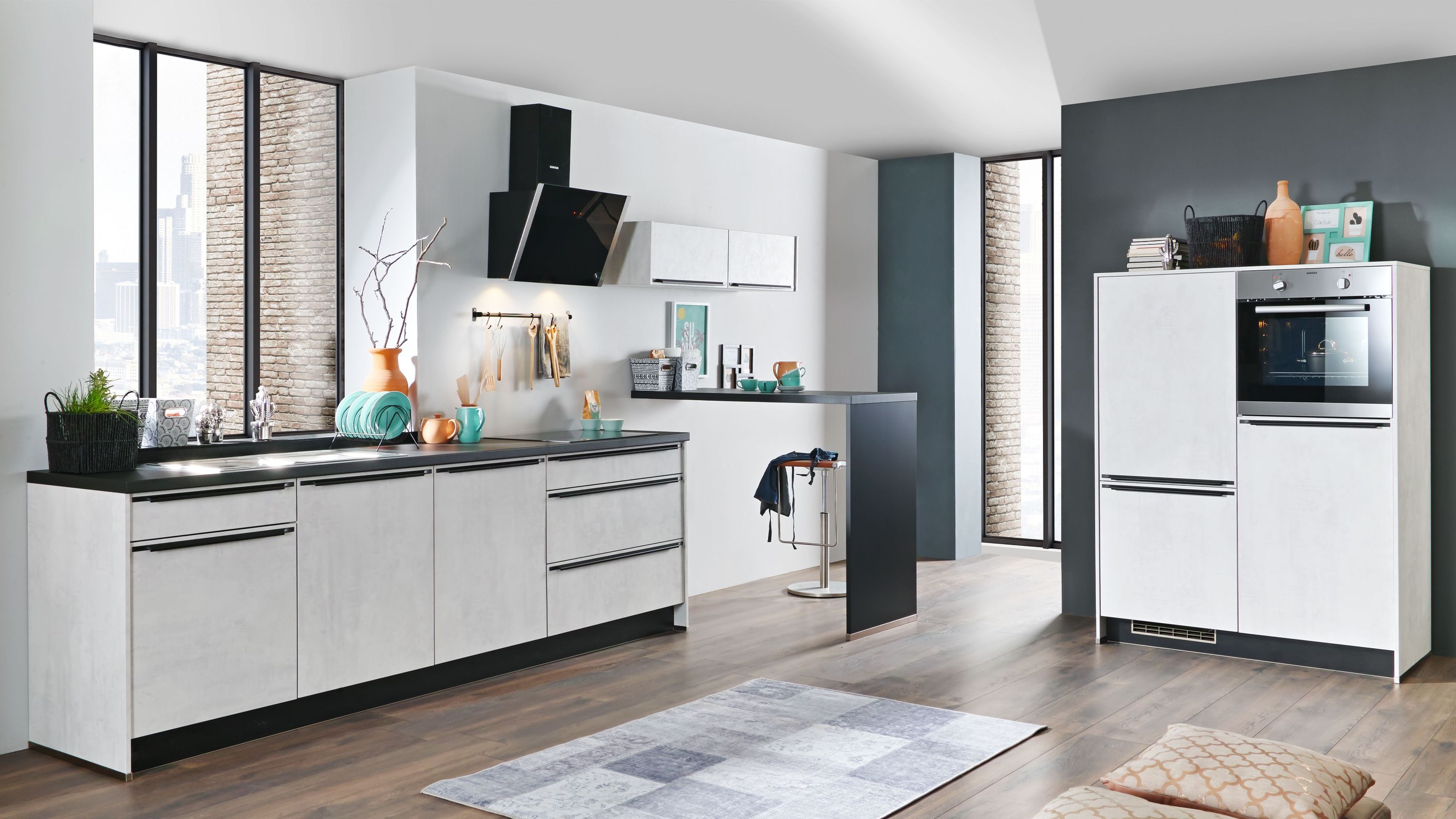 Moderne Designküche mit Insel und Tageslicht Weiße Küche mit Insel schwarzer Arbeitsplatte Holzfußboden Edelstahlgeräten Tageslicht Deko und Teppich.