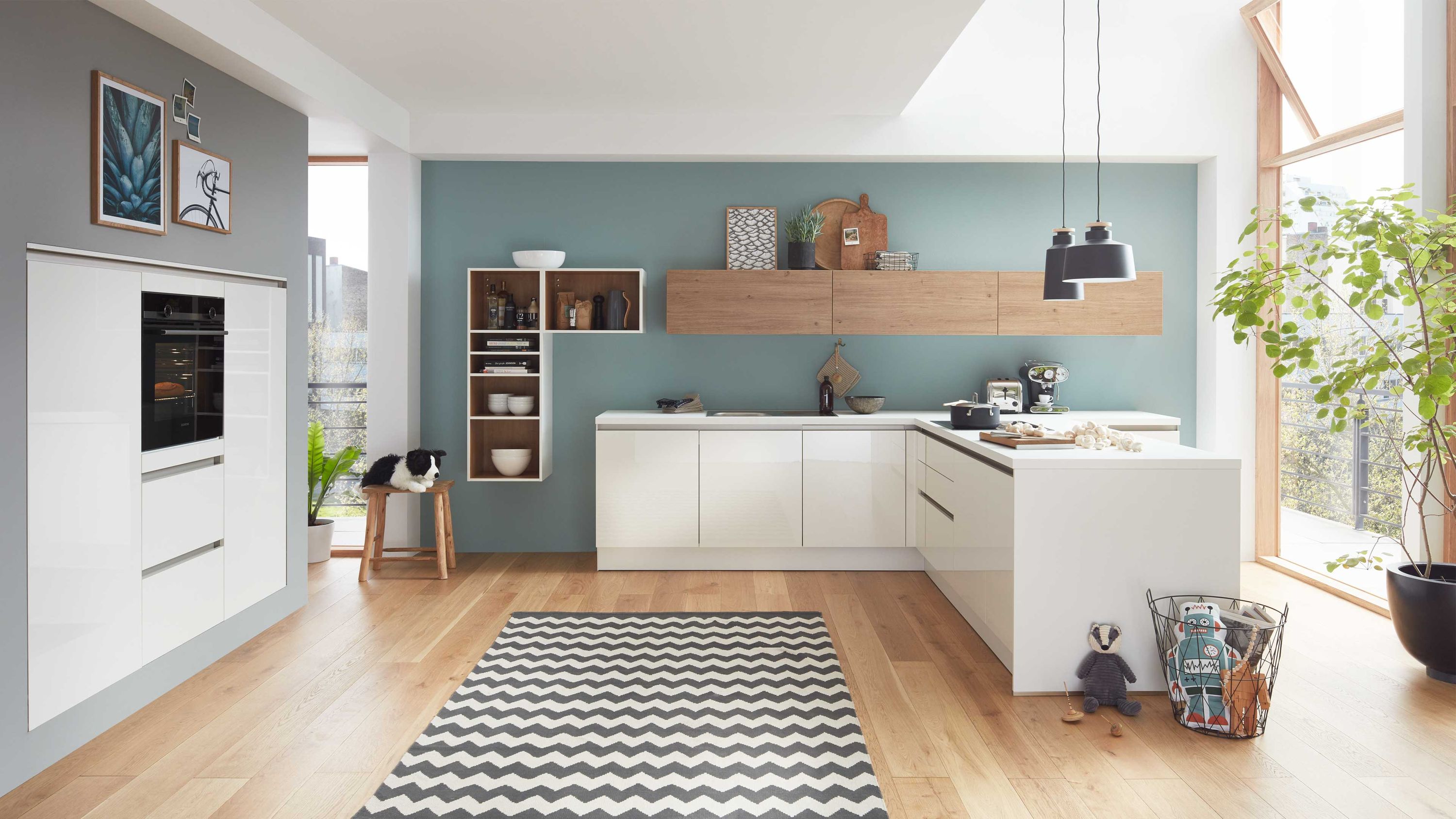 Weiße Küche mit Holzarbeitsplatte blauer Wand gemustertem Teppich Fensterlicht offenen Regalen Hängelampen