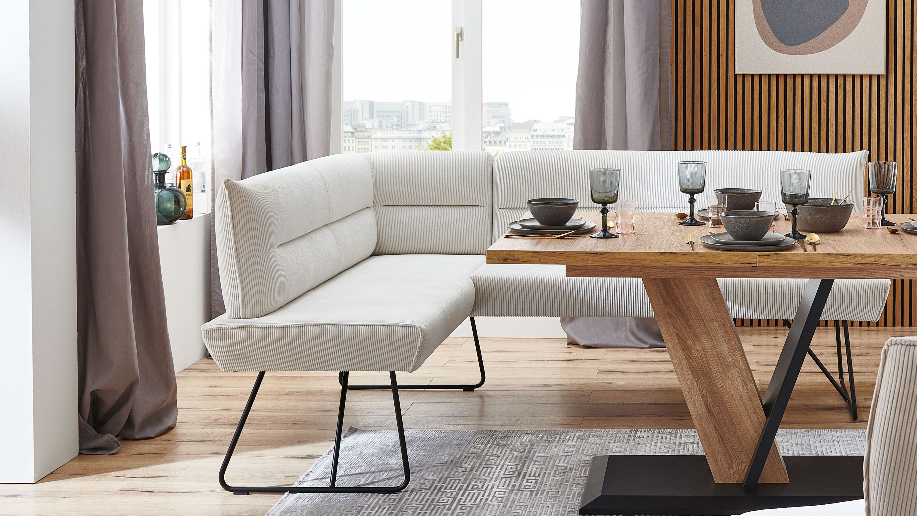 Eckbank mit cremeweißem Cordbezug und schwarzem Metallgestell in modernem Esszimmer mit Holztisch