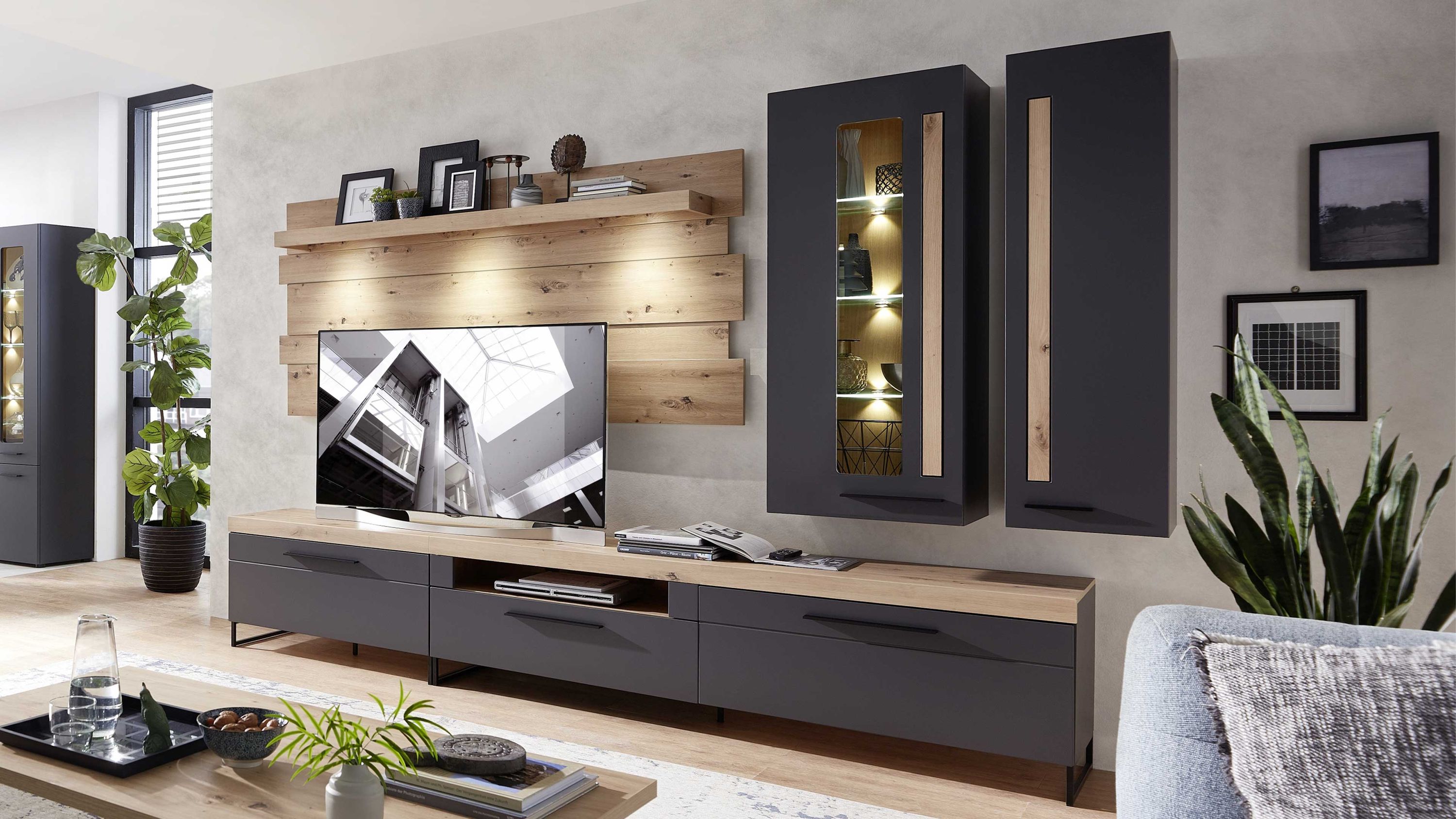 Fünfteilige Wohnwand mit flachen Schränken in dunklem Grau und Holzpaneelen an der Wand