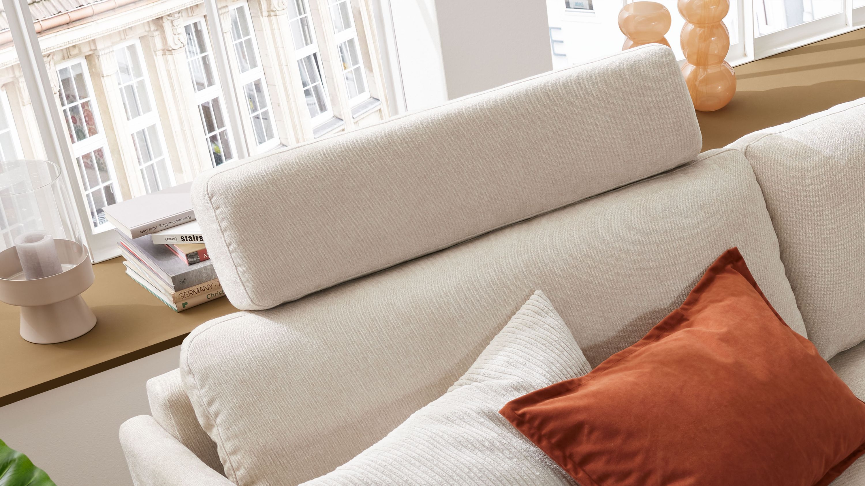 Naturfarbene rechteckige Kopfstütze mit Strukturbezug auf einem hellen Sofa