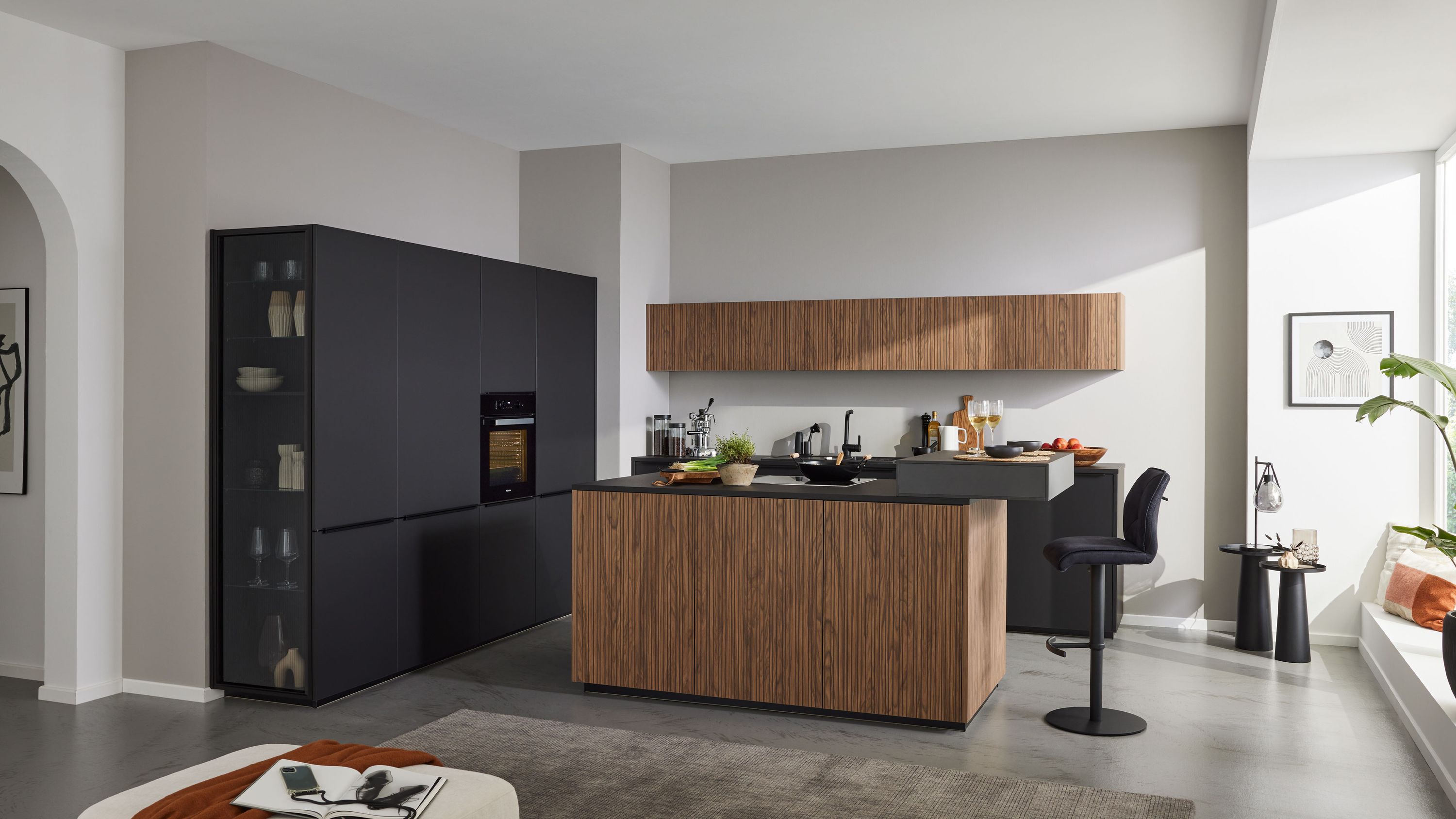 Moderne Inselküche mit Holzfronten schwarzen Hochschränken Hängeschrank und Barbereich mit Hockern.