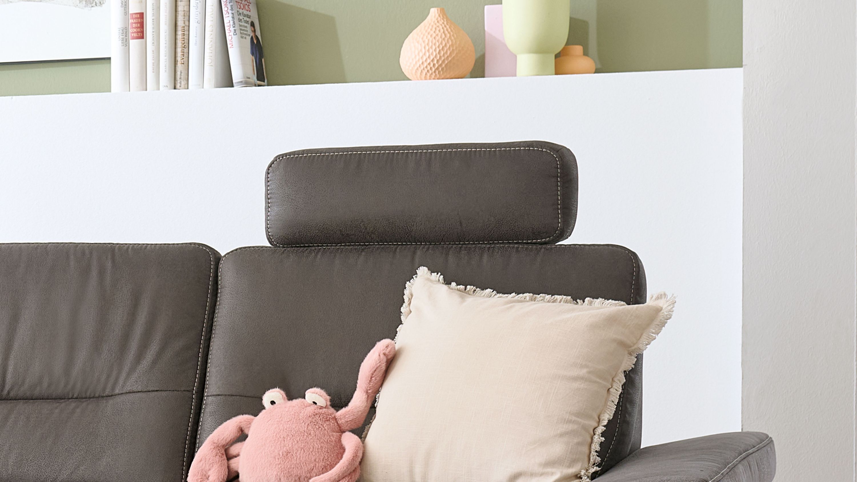 Anthrazitfarbene Kopfstütze mit rechteckiger Form und sichtbaren Nähten auf einem Sofa