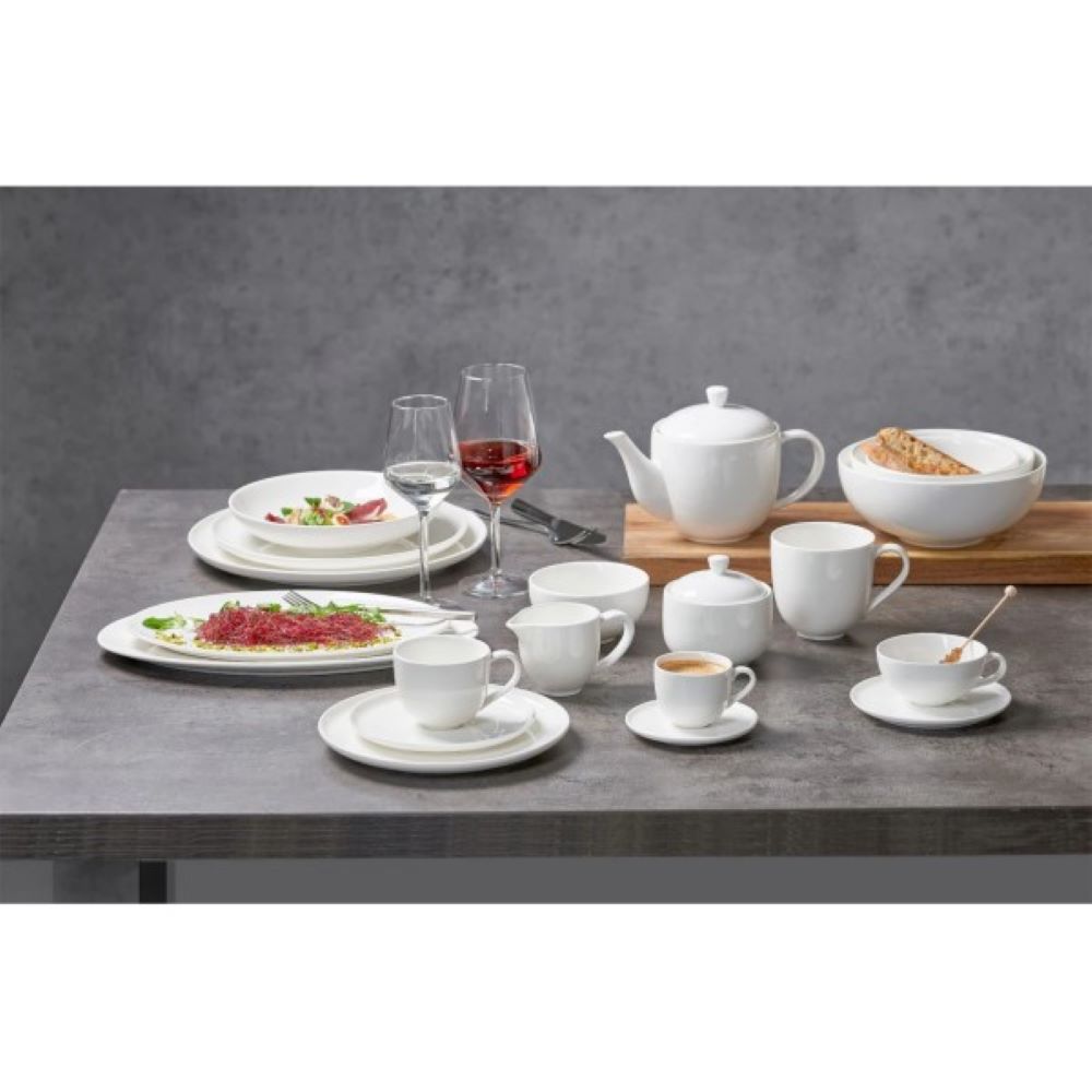 Gedeckter Tisch mit Porzellangeschirr Gedeckter Tisch mit weißem Porzellangeschirr, Gläsern und Tellern mit Speisen, frontal aufgenommen.