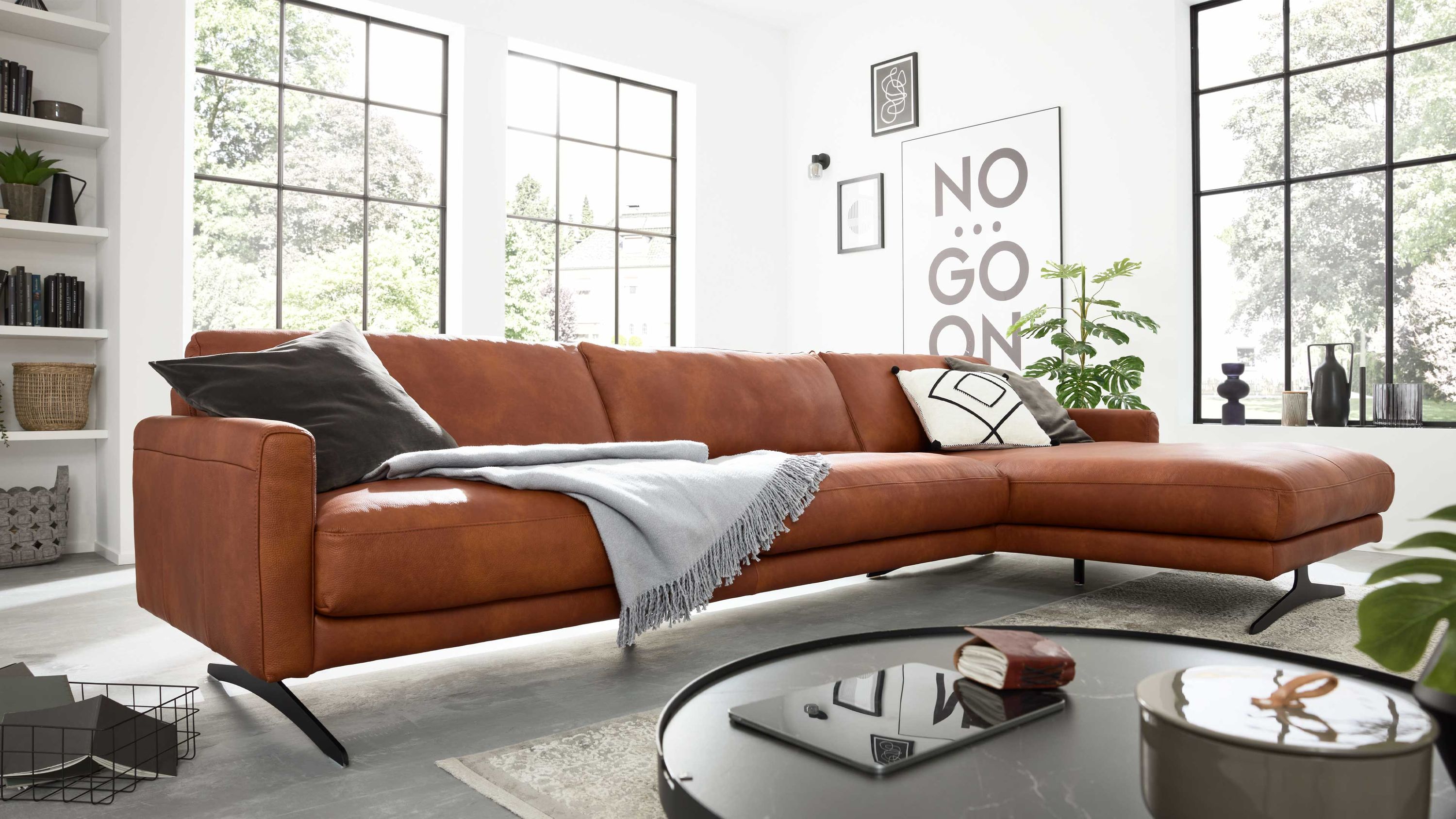 Ecksofa mit cognacfarbenem Lederbezug Ecksofa mit cognacfarbenem Lederbezug und schwarzen Metallfüßen in modernem Wohnzimmer