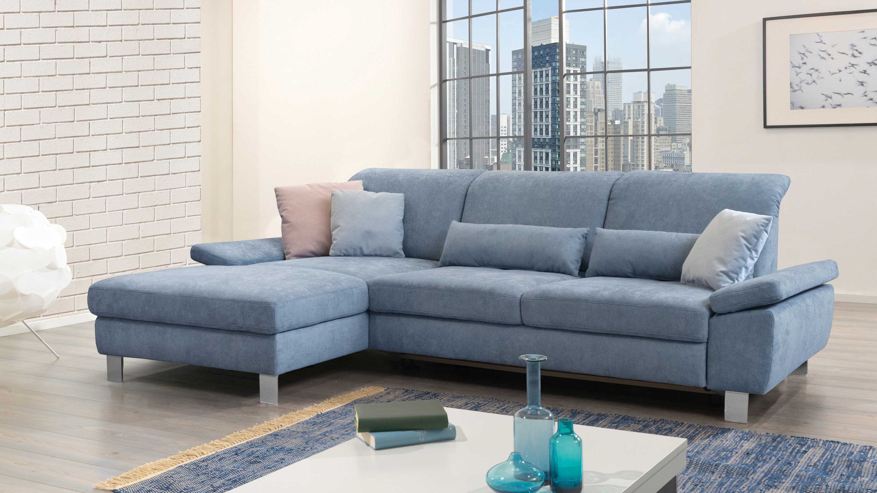 Ecksofa mit taubenblauem Stoffbezug schwarzen Metallfüßen und mehreren Kissen in einem modernen Wohnzimmer