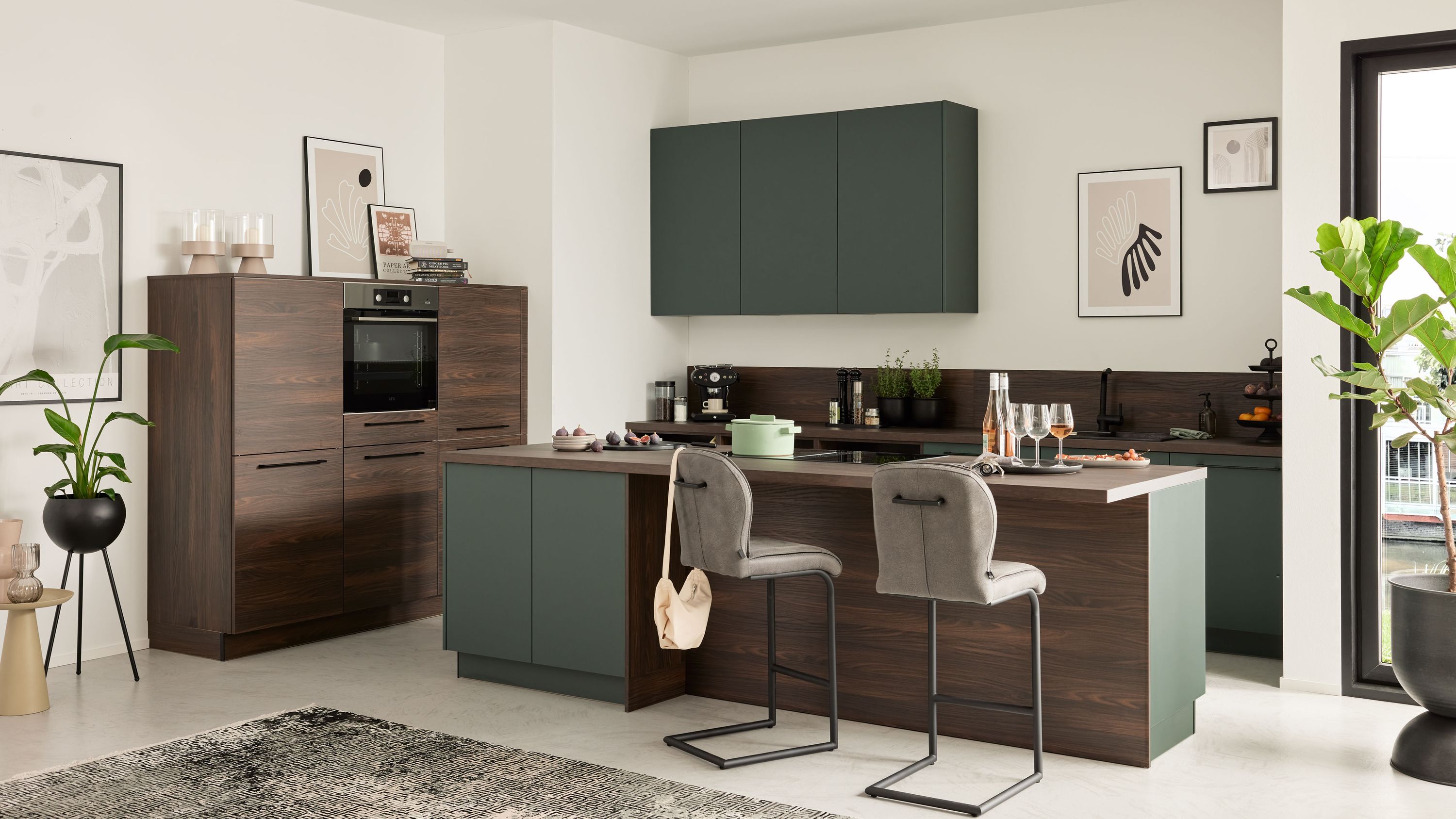 L-Küche in Dunkelgrün und Holzoptik mit Kochinsel Barhockern Einbauofen und moderner Beleuchtung.