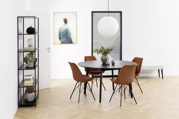 Moderner Essbereich mit sechs orangefarbenen Stühlen  rundem Tisch und schwarzem Regal vor weißer Wand mit Wandkunst