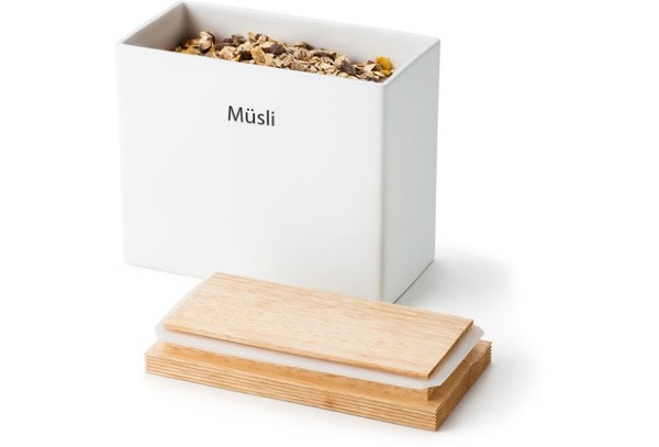 Müslibox mit Holzdeckel Weiße Box mit der Aufschrift „Müsli“, gefüllt mit Müsli, Holzdeckel liegt davor, freigestellt vor weißem Hintergrund