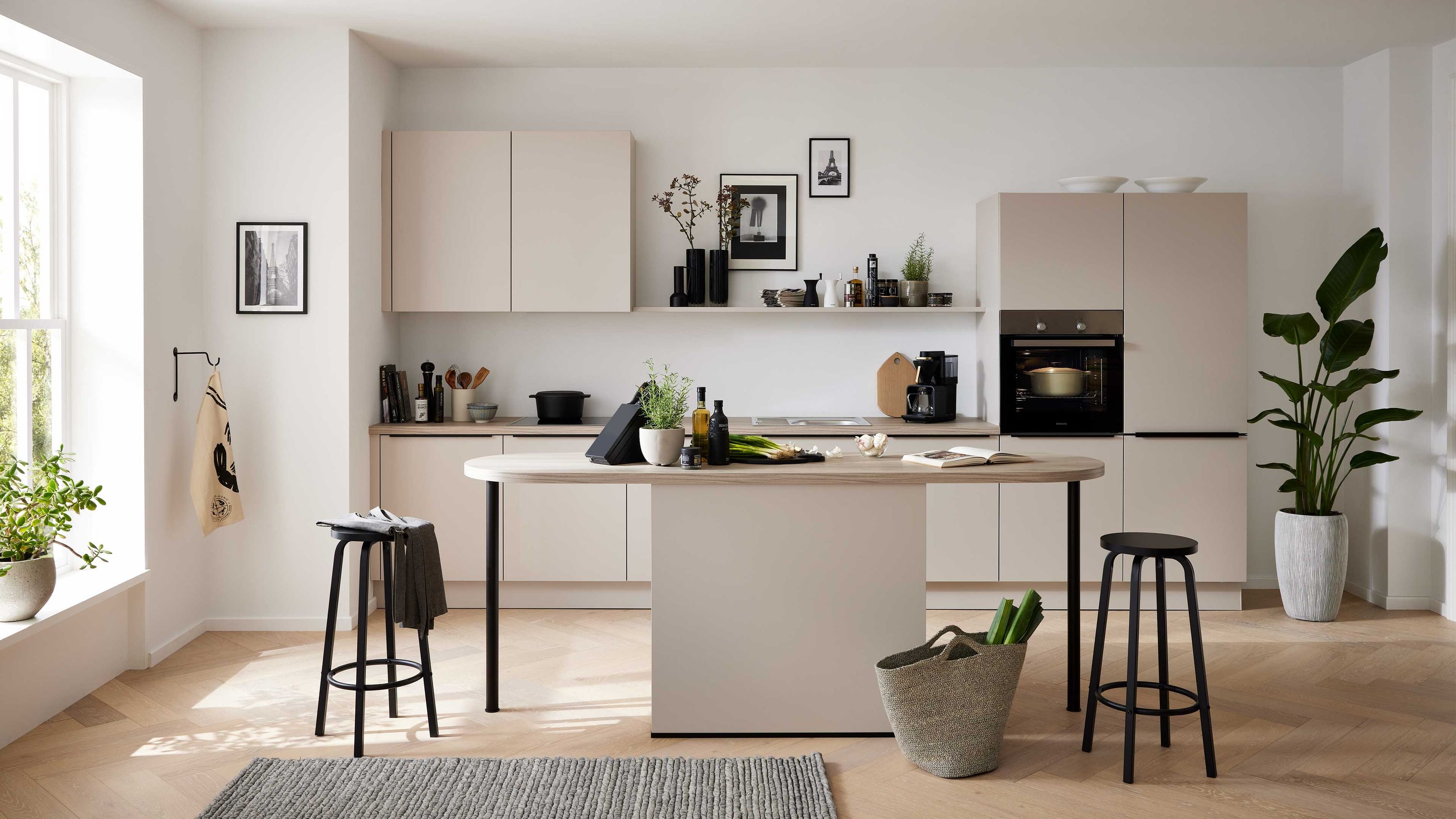 Beige Küche mit Kochinsel und Barhockern. Helle Küche in Beige mit Kochinsel Barhockern offenen Regalen Einbauofen und großen Fenstern.
