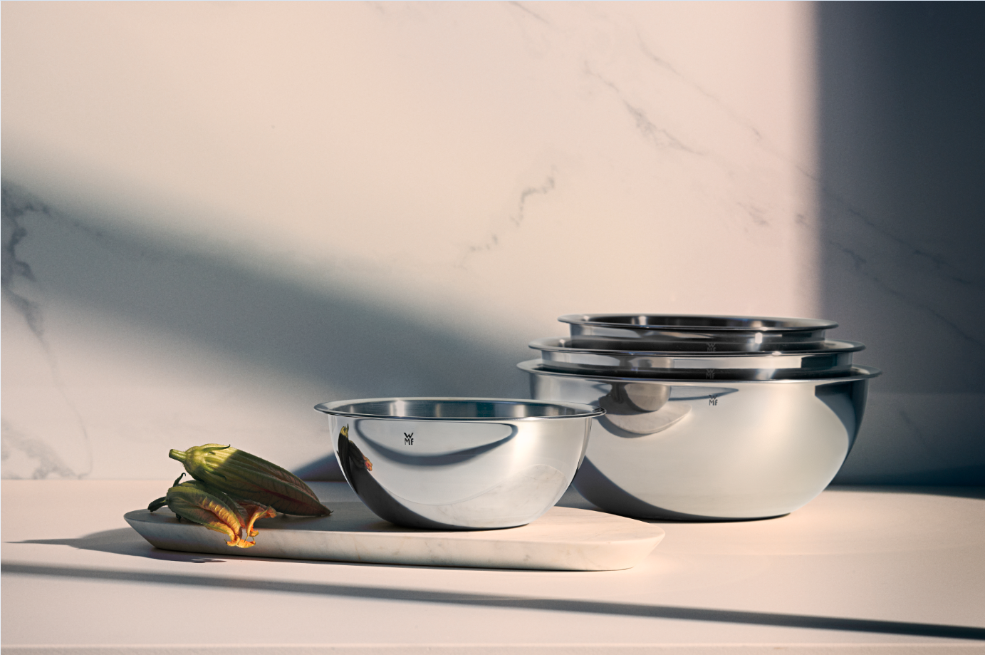 Vier runde Küchenschüsseln aus Edelstahl in verschiedenen Größen auf weißer Oberfläche