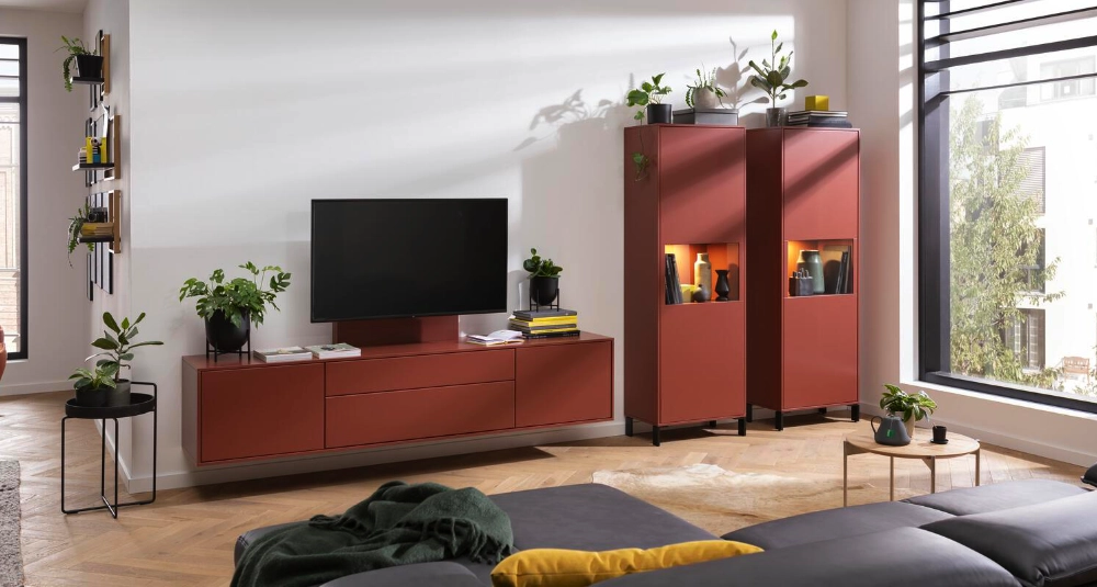 Wohnzimmer mit moderner roten Wohnwand, TV-Board und beleuchteten Vitrinen, dekoriert mit Pflanzen und Accessoires.