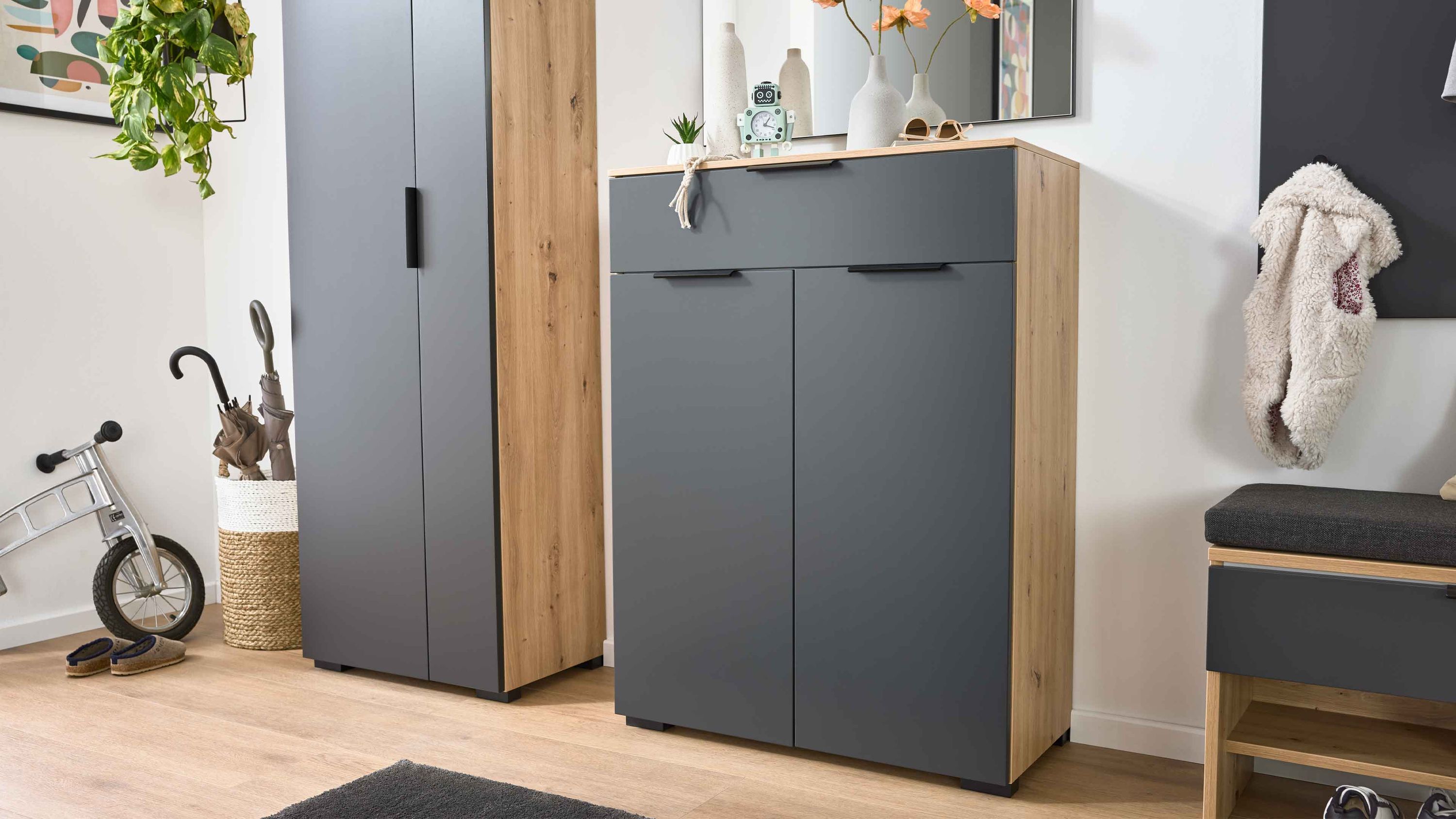 Kombikommode mit einer Schublade und zwei Türen in anthrazit und holzfarben neben einem hohen Schrank und einer Sitzbank