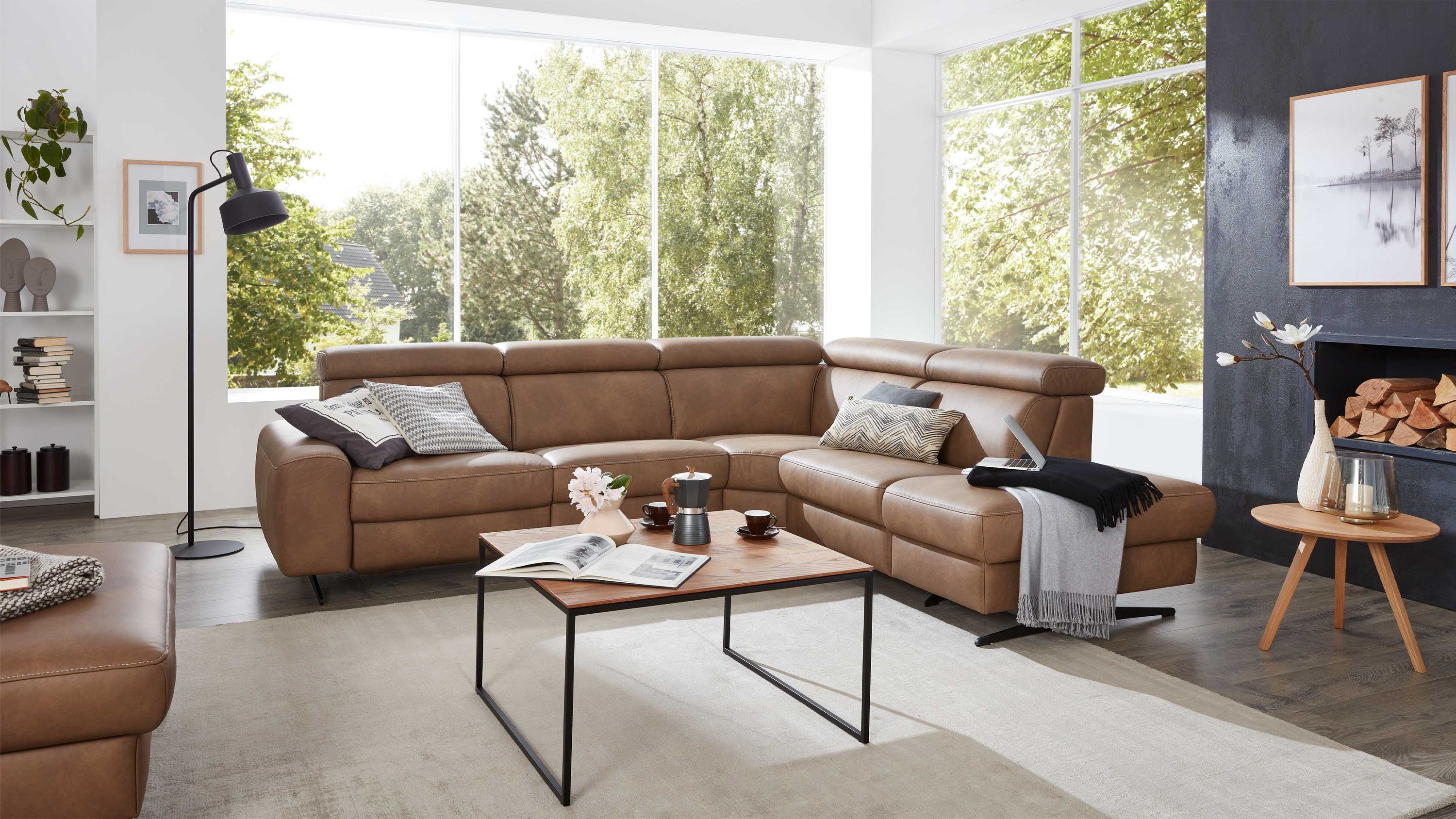 Braunes Ecksofa mit verstellbaren Kopfstützen Ecksofa mit verstellbaren Kopfstützen in braunem Leder in modernem Wohnzimmer mit großen Fenstern