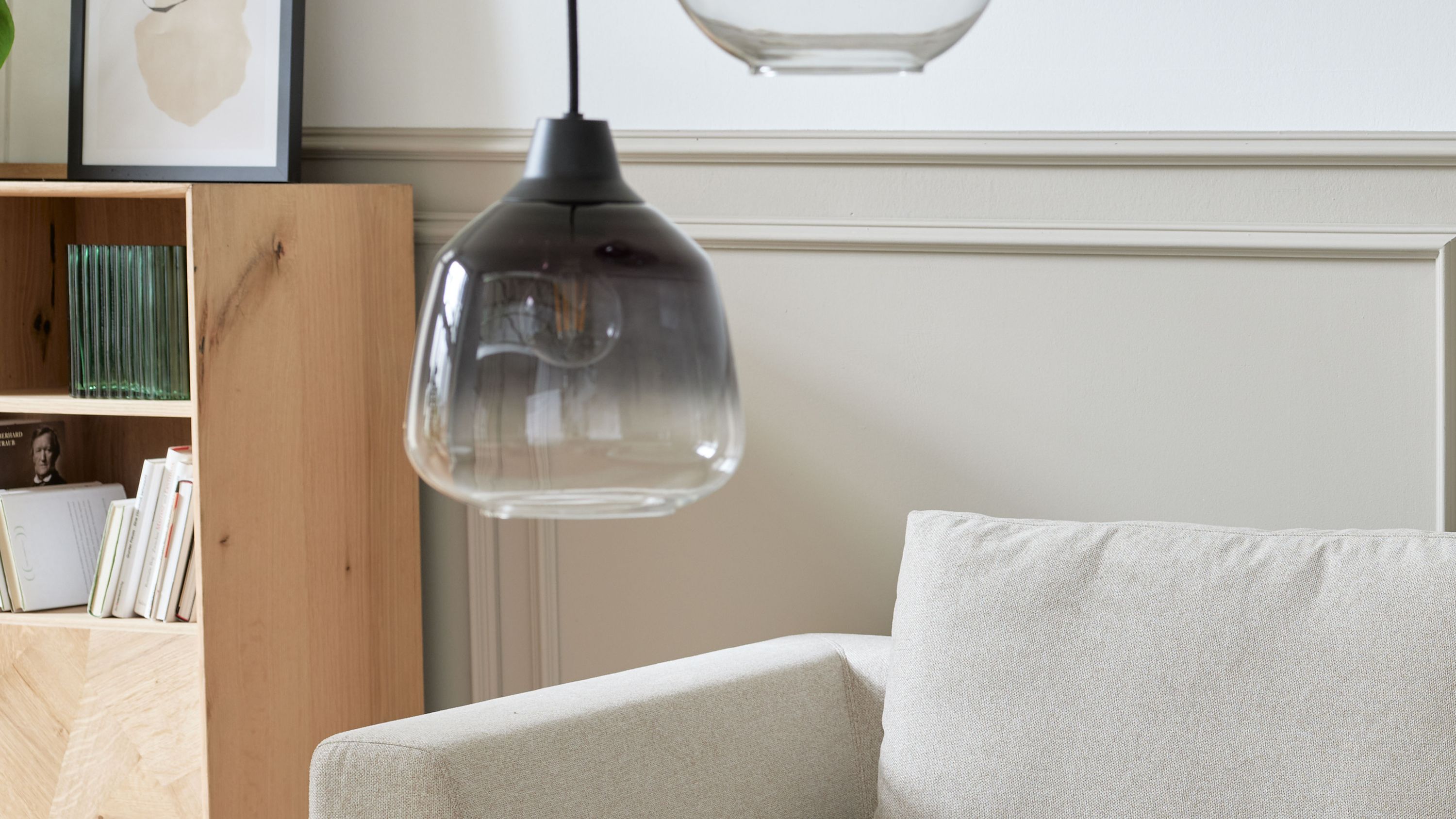 Hängeleuchte mit schwarzem Glas und Verlauf Hängeleuchte mit rundem schwarzem Glas und Verlauf zu transparent hängend über einem hellen Sofa