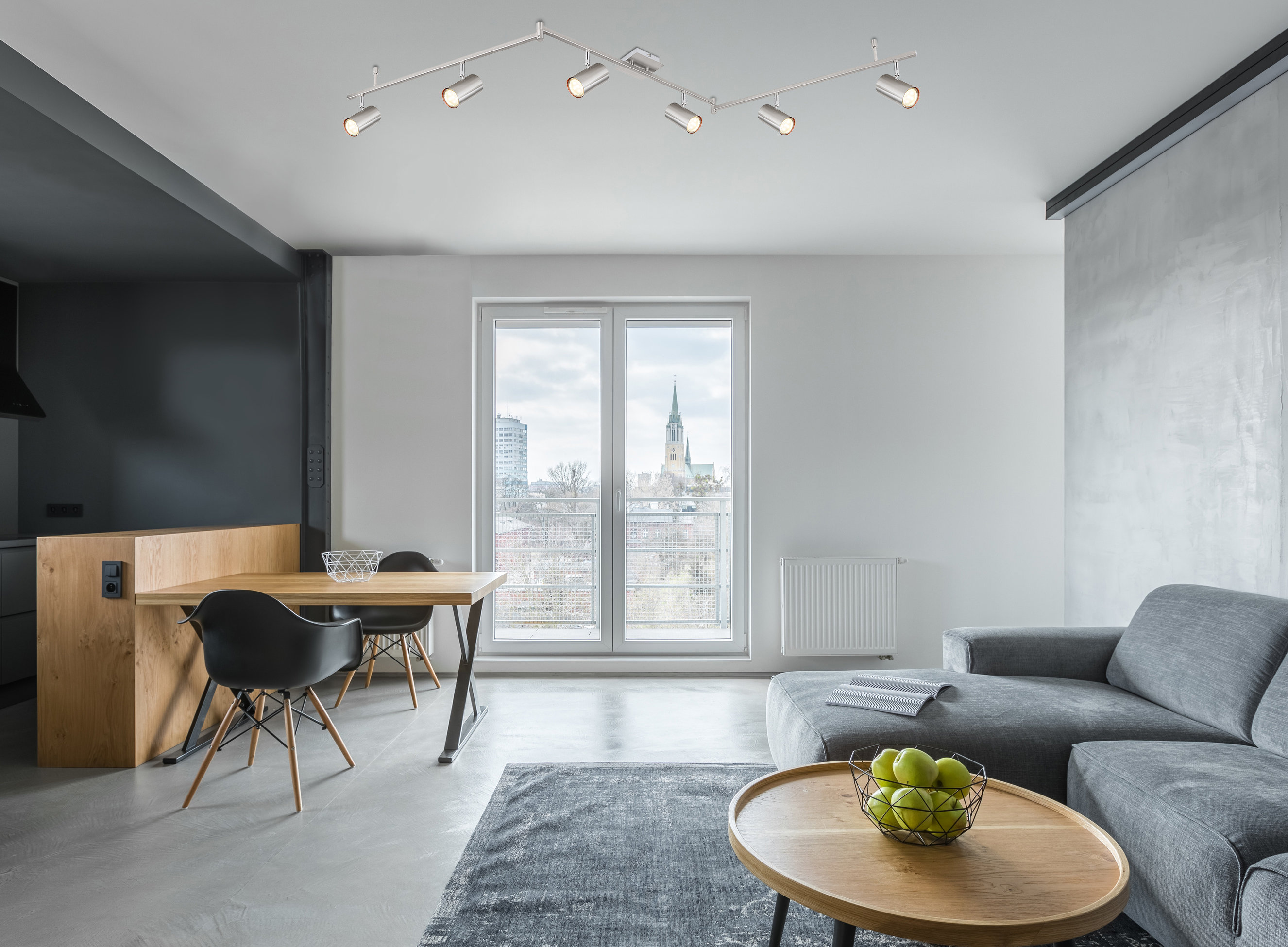 Z-förmig montierter LED-Deckenstrahler mit sechs Spots  zentral an heller Wohnzimmerdecke über Couch und Tisch installiert