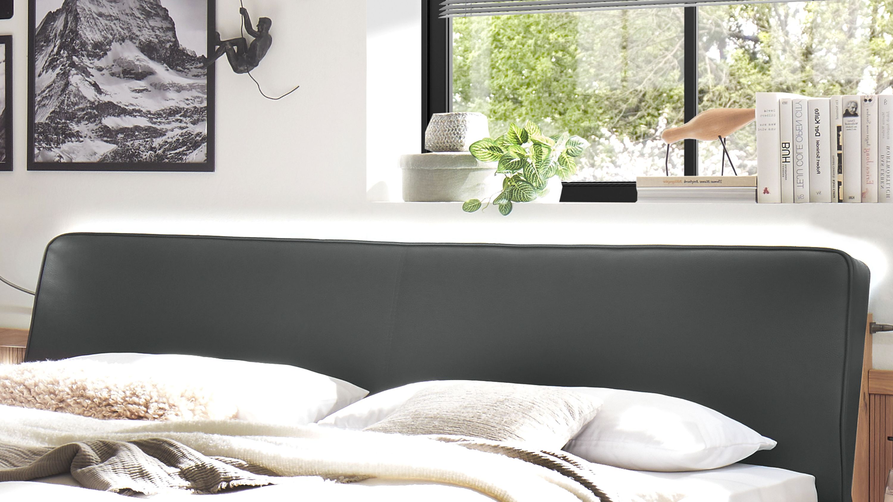 Schwarzes gepolstertes Kopfteil mit integrierter Beleuchtung über einem Bett mit weißen Kissen und Decken