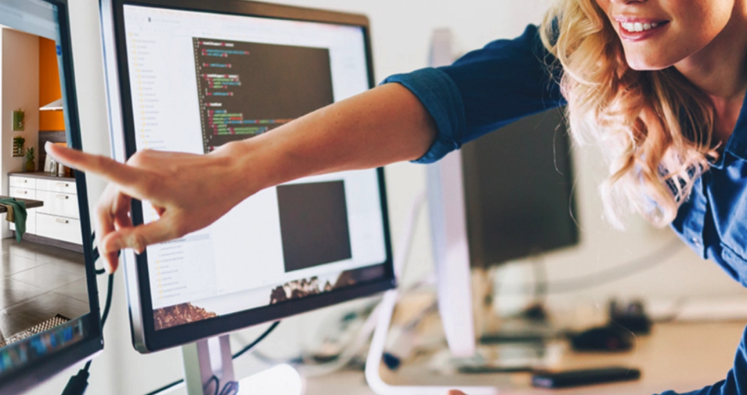 Person zeigt auf Monitor mit Code und Raumvisualisierung, moderner Arbeitsplatz mit Bildschirm, Softwareentwicklung und Büroplanung