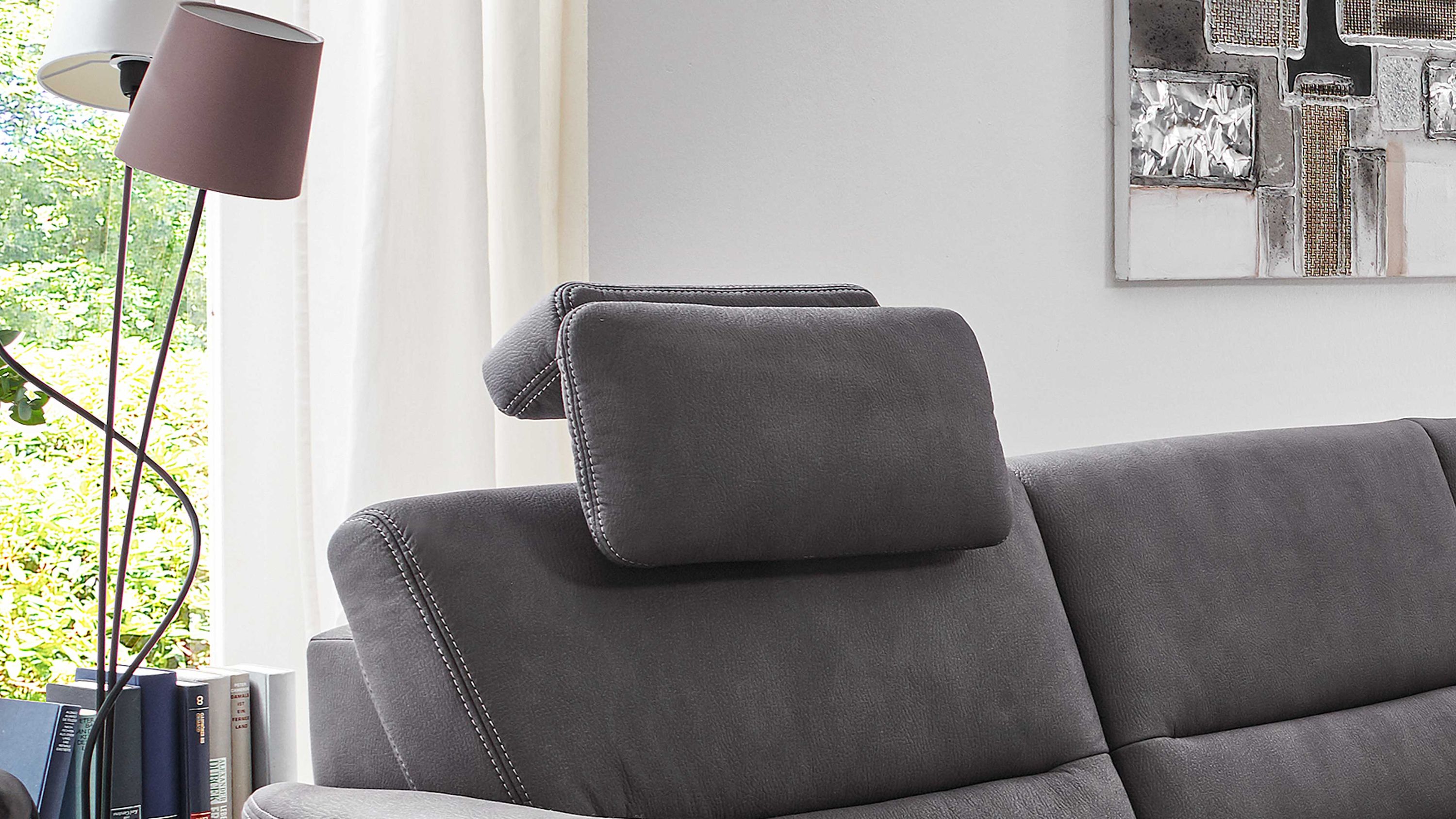 Kopfstütze auf grauem Sofa Graue Kopfstütze auf grauem Sofa mit sichtbaren Nähten in einem hellen Wohnzimmer
