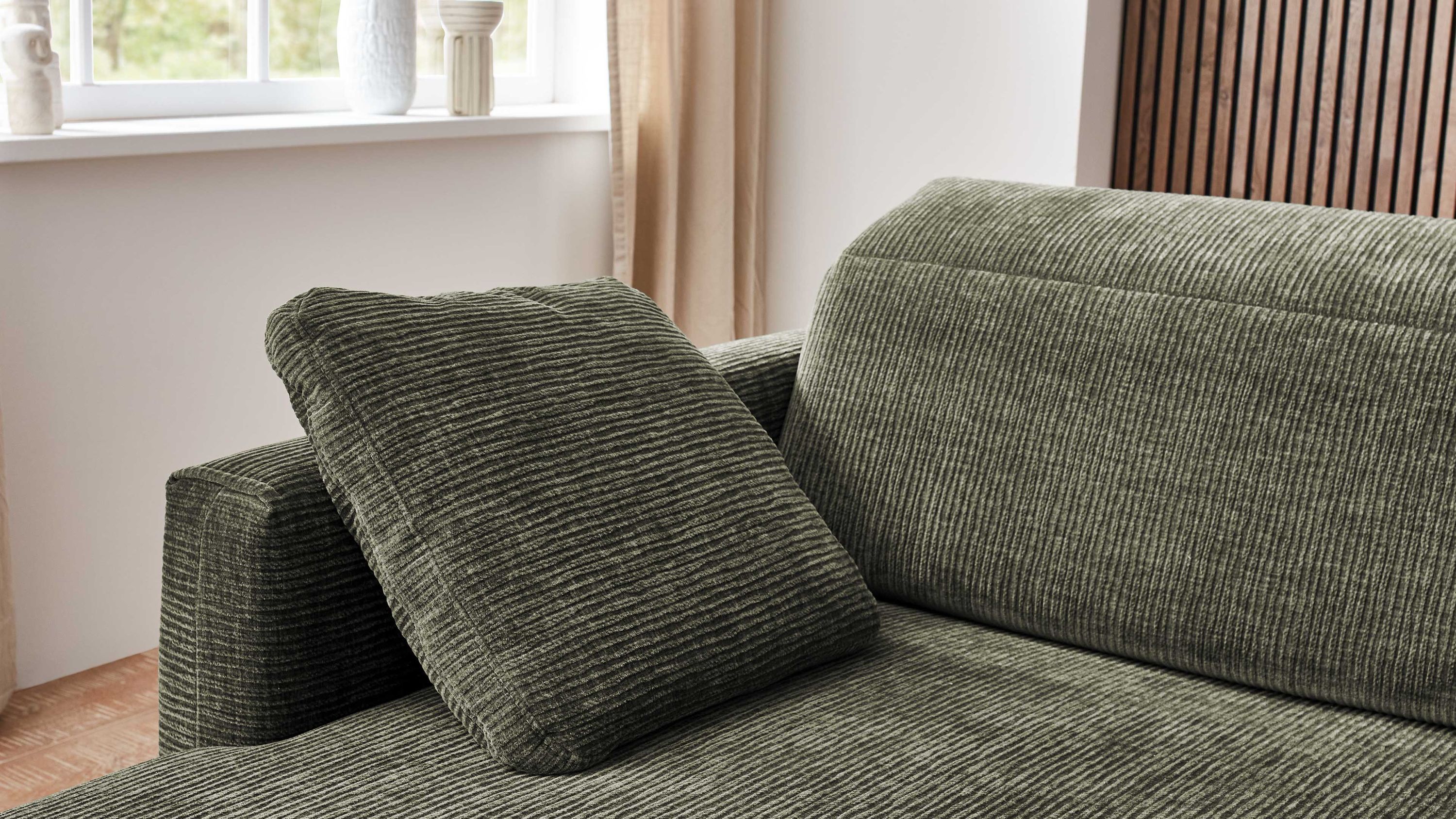 Quadratisches Armlehnkissen in olivgrün mit feiner Streifenstruktur auf Sofa mit breiter Armlehne