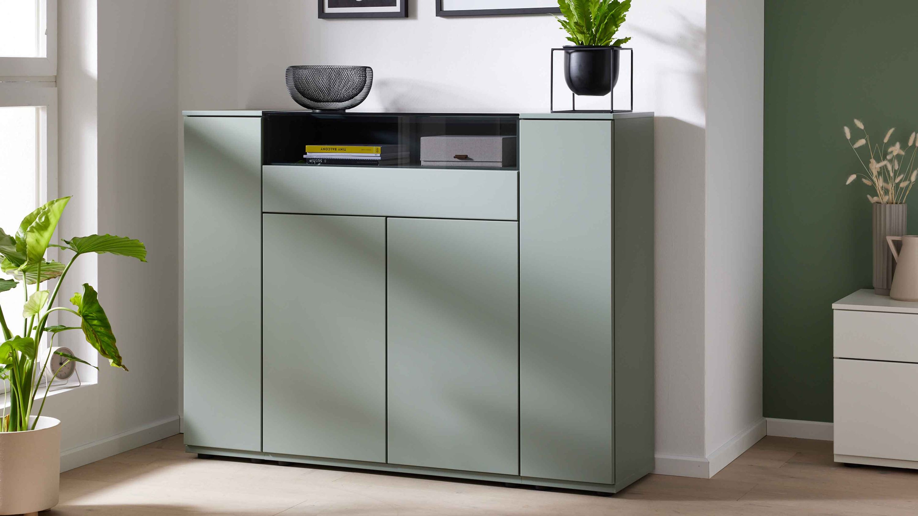 Hohes Sideboard mit vier Türen und einer Schublade in grün mit offenem Fach und Dekoration