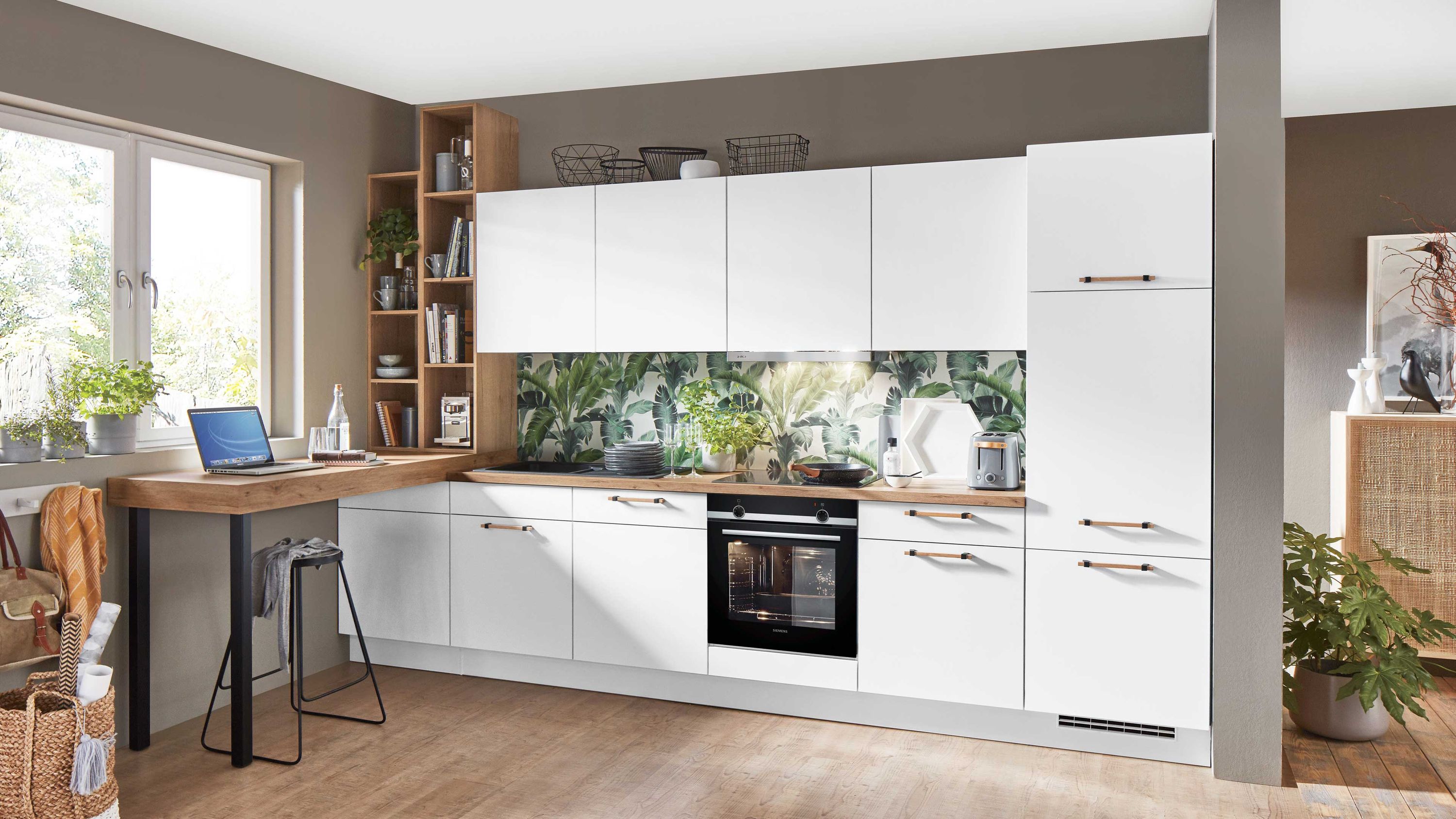 Weiße Küchenzeile mit Holzarbeitsplatte integriertem Arbeitsplatz Einbauofen und Rückwand mit Naturmotiv.