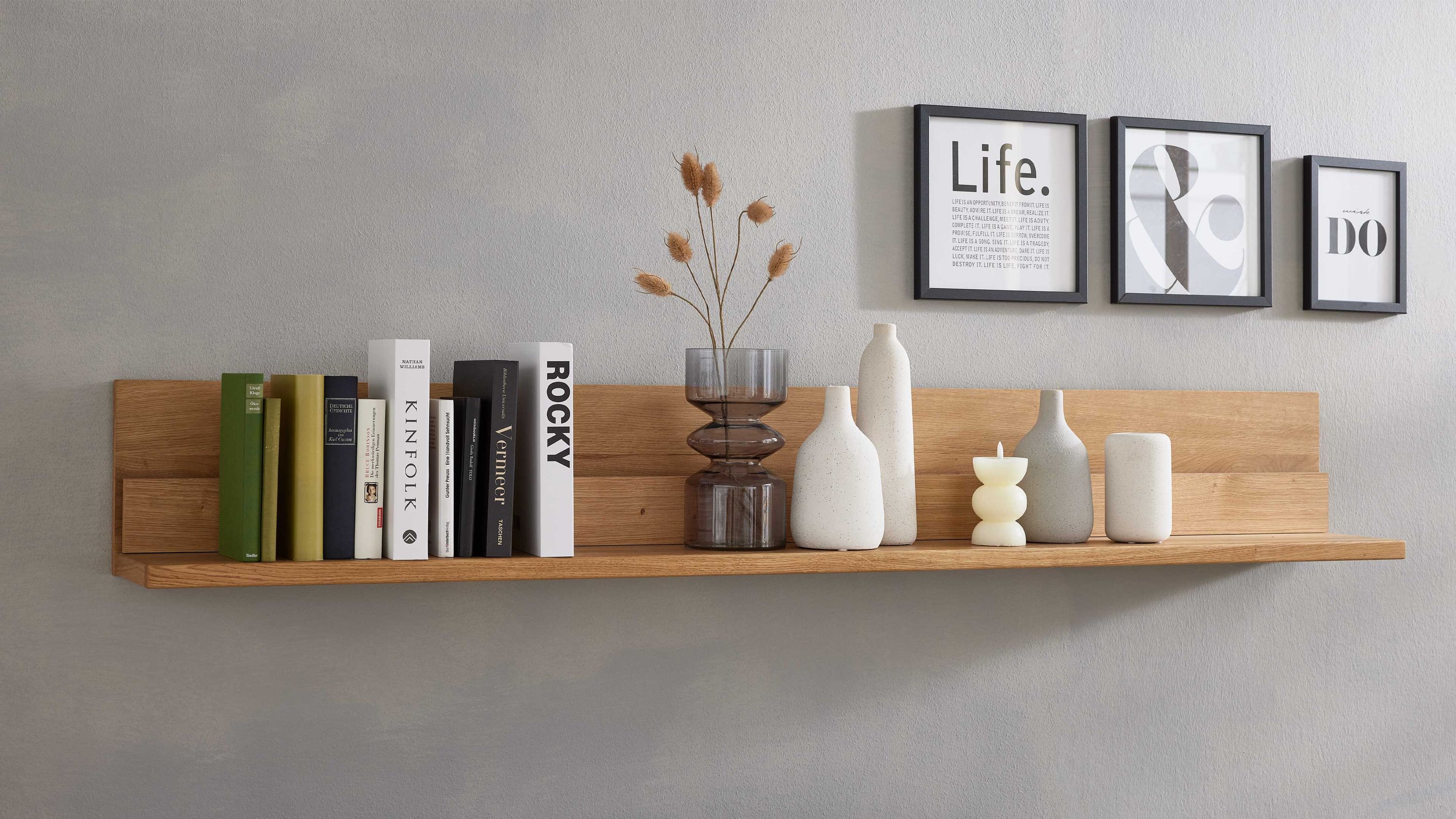 Wandregal aus hellem Holz mit Büchern und Vasen Wandregal aus hellem Holz mit Büchern und Dekorationsvasen an grauer Wand
