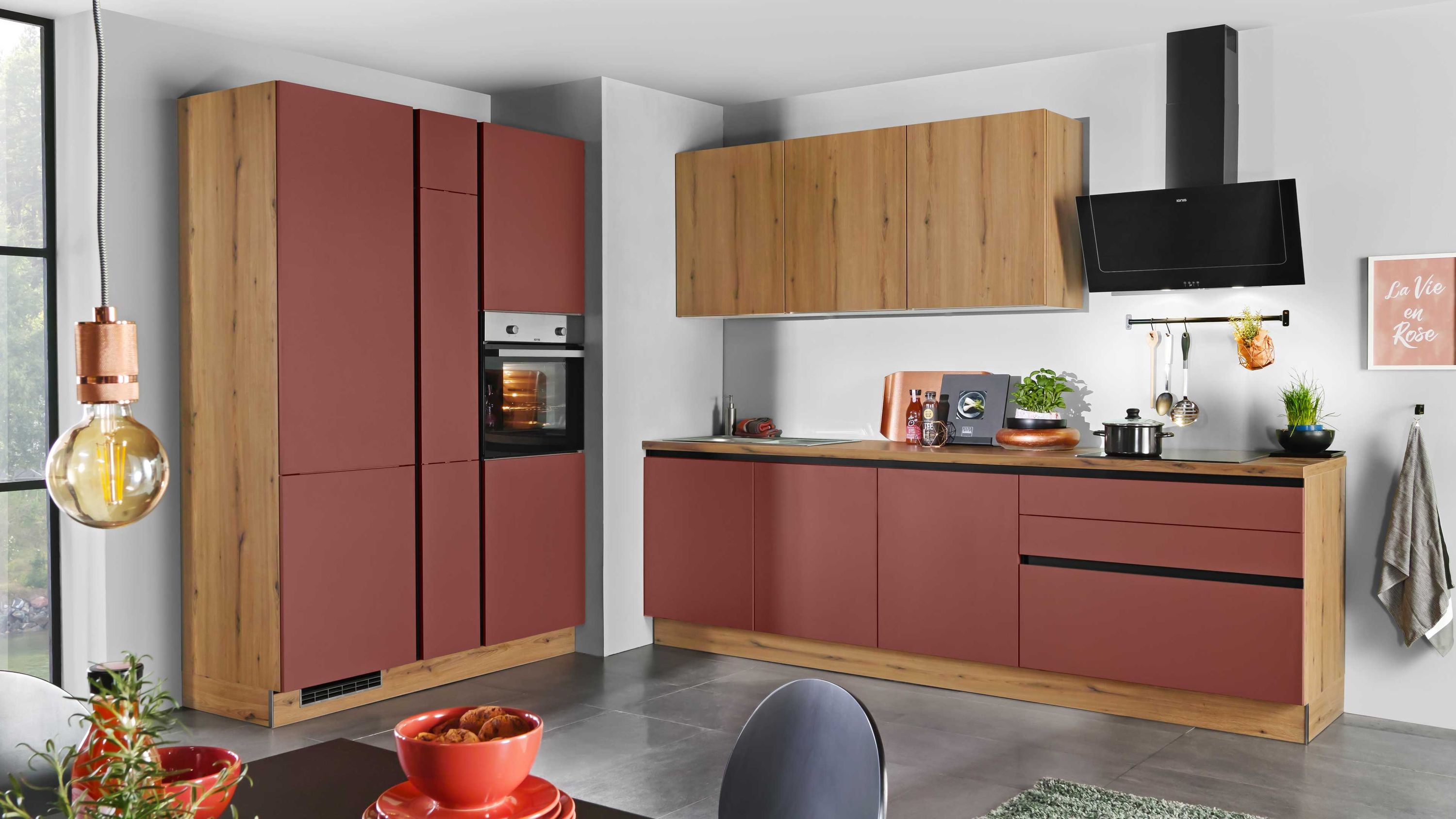 Moderne Küche in Rot und Holzoptik mit Hängeschränken und schwarzer Dunstabzugshaube.